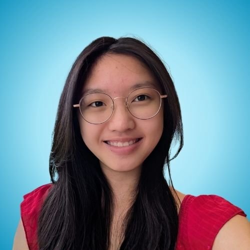 A young woman with long dark hair, wearing glasses and a red top, smiling against a light blue background.