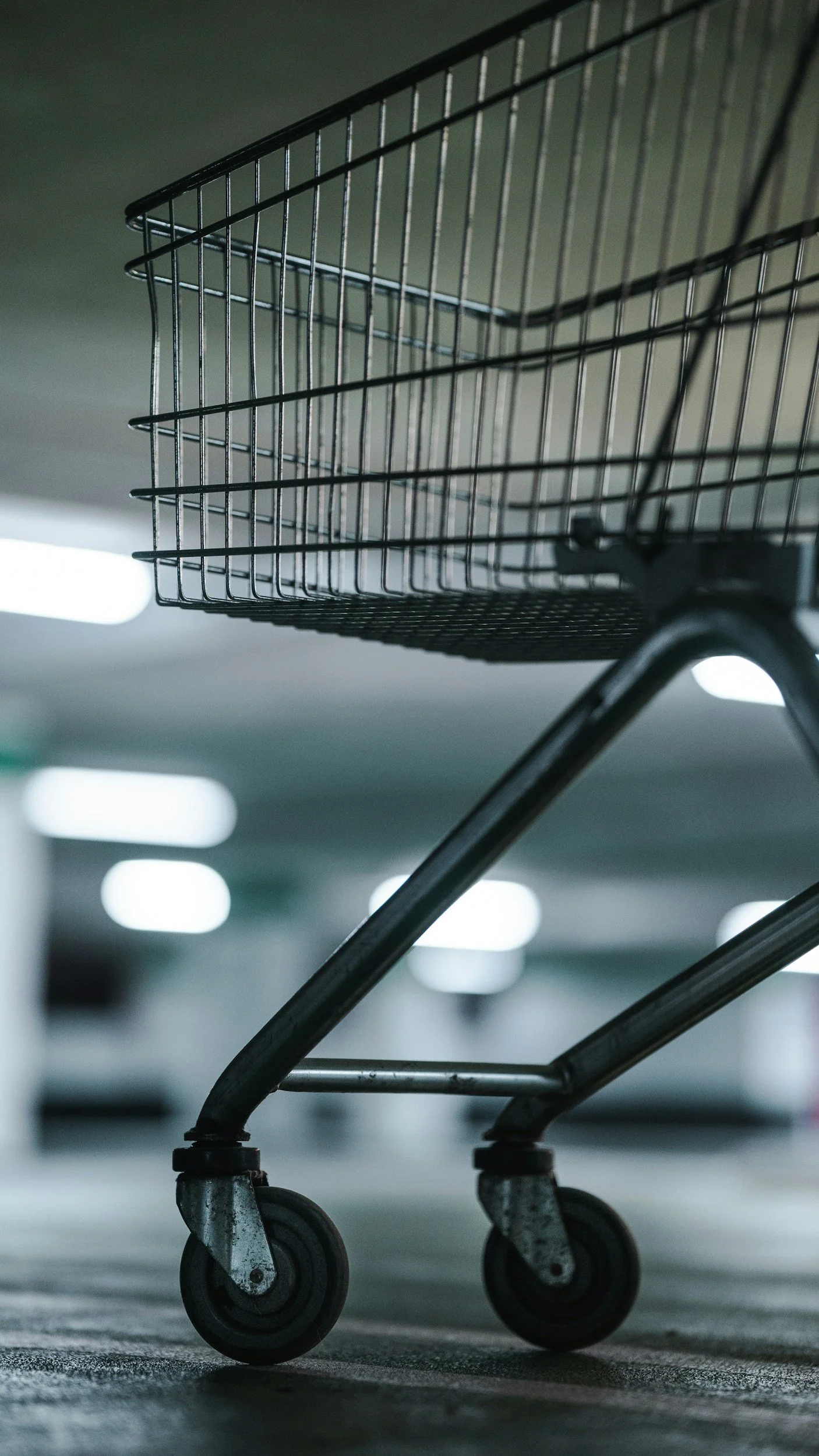 Empty shopping cart in indoor parking garage or store, low angle shot.