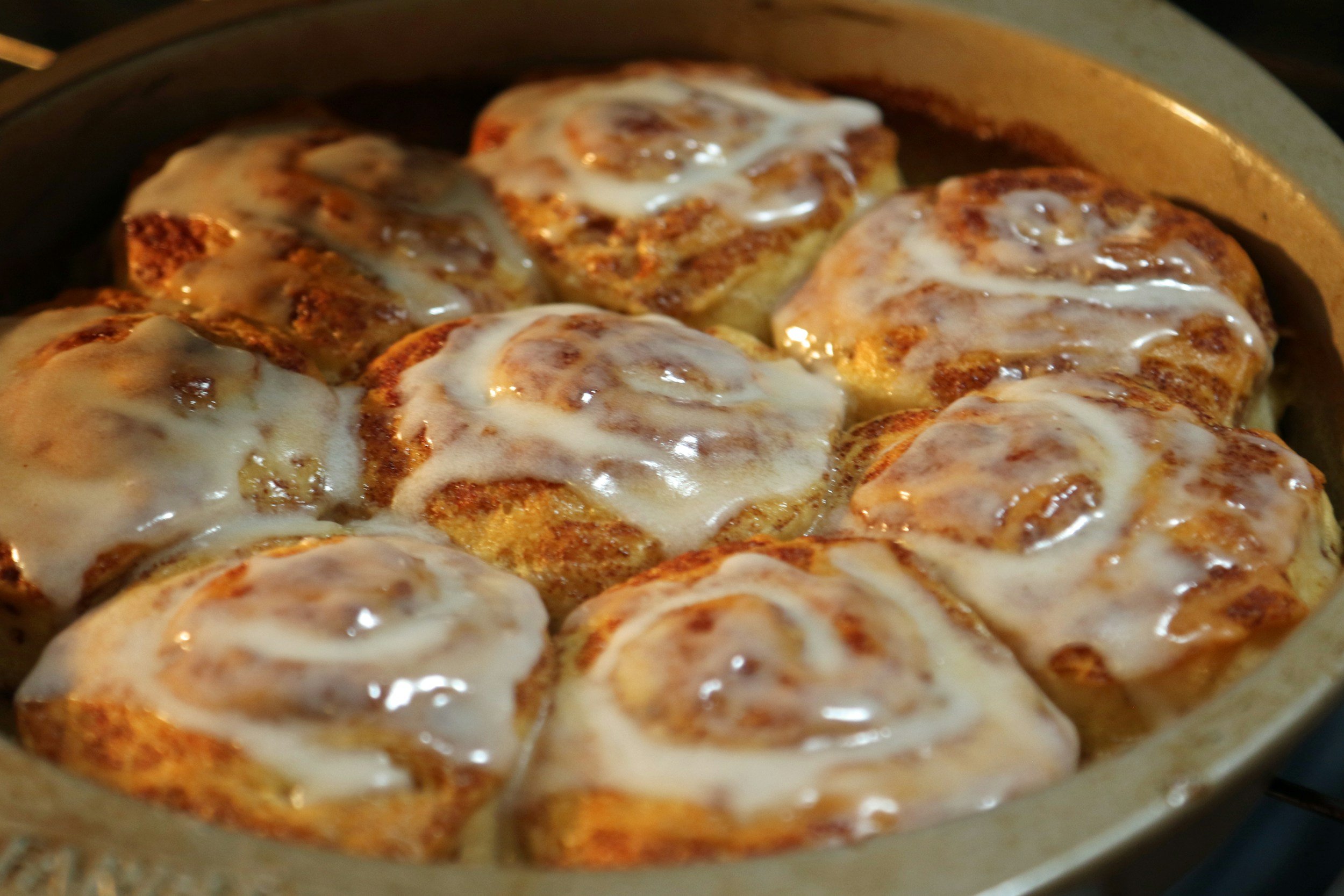 Hot cinnamon rolls with frosting in a baking dish.