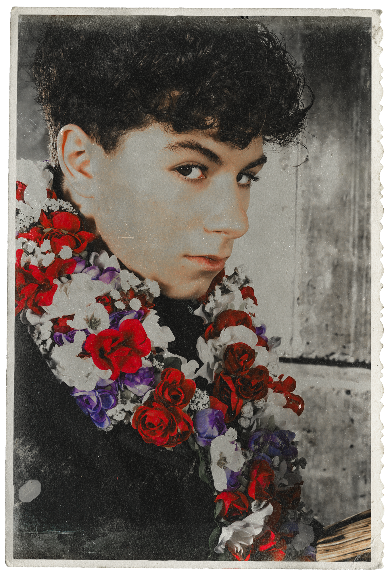 Jonah from Freeze The Fall looking slightly to the side, wearing a black top and adorned with a large multicoloured flower necklace of red, white, purple, and black flowers.