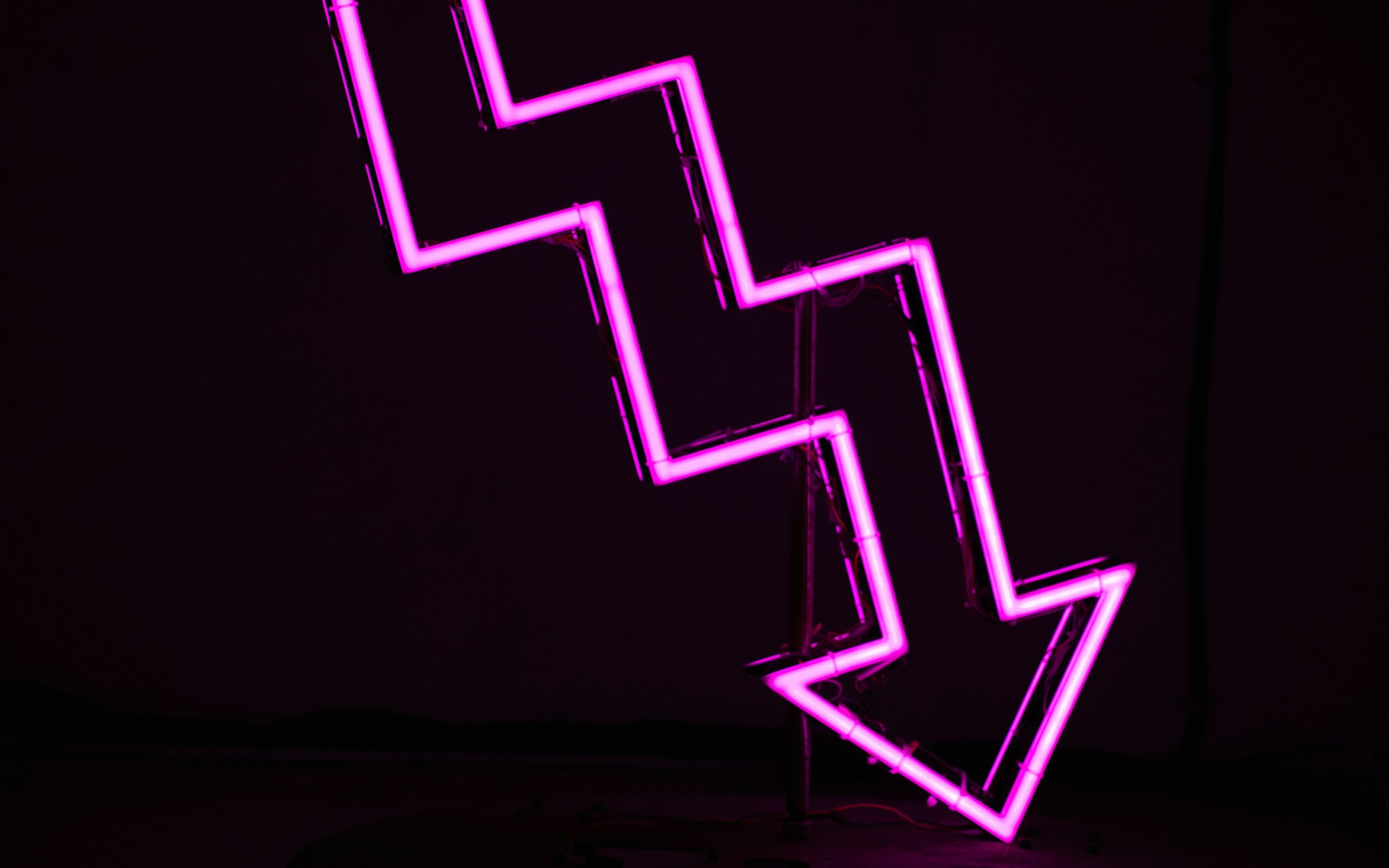 Neon purple lightning bolt sign against a black background.