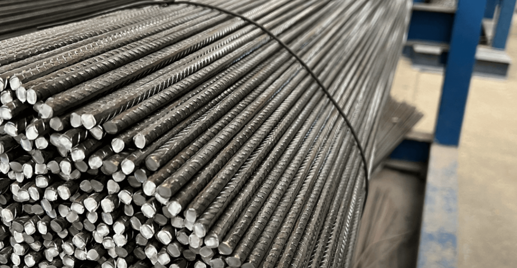 Close-up of a large bundle of steel rebar, stacked on a metal cart in an industrial setting.
