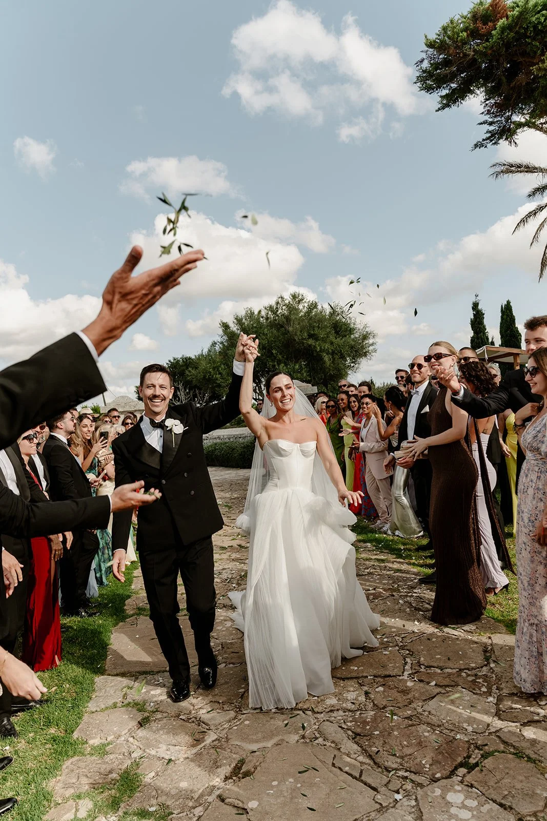 Bride and groom walking through guests during ceremony exit with confetti in Menorca