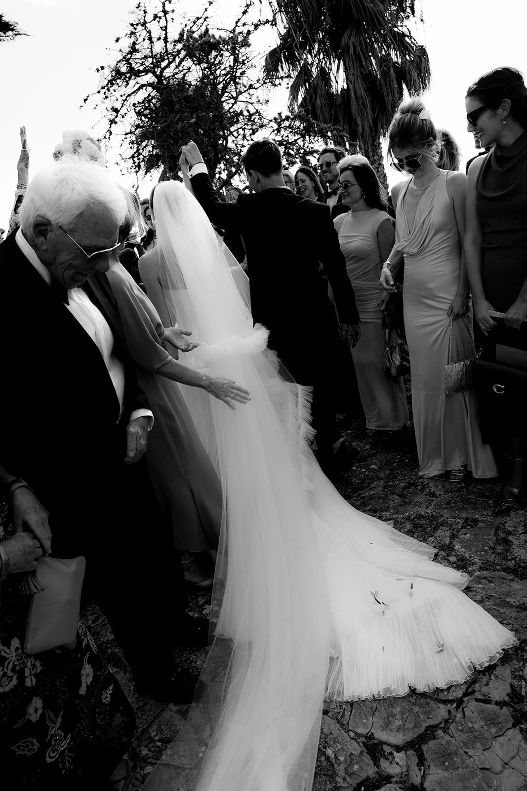 Bride and groom leaving ceremony surrounded by guests in black and white