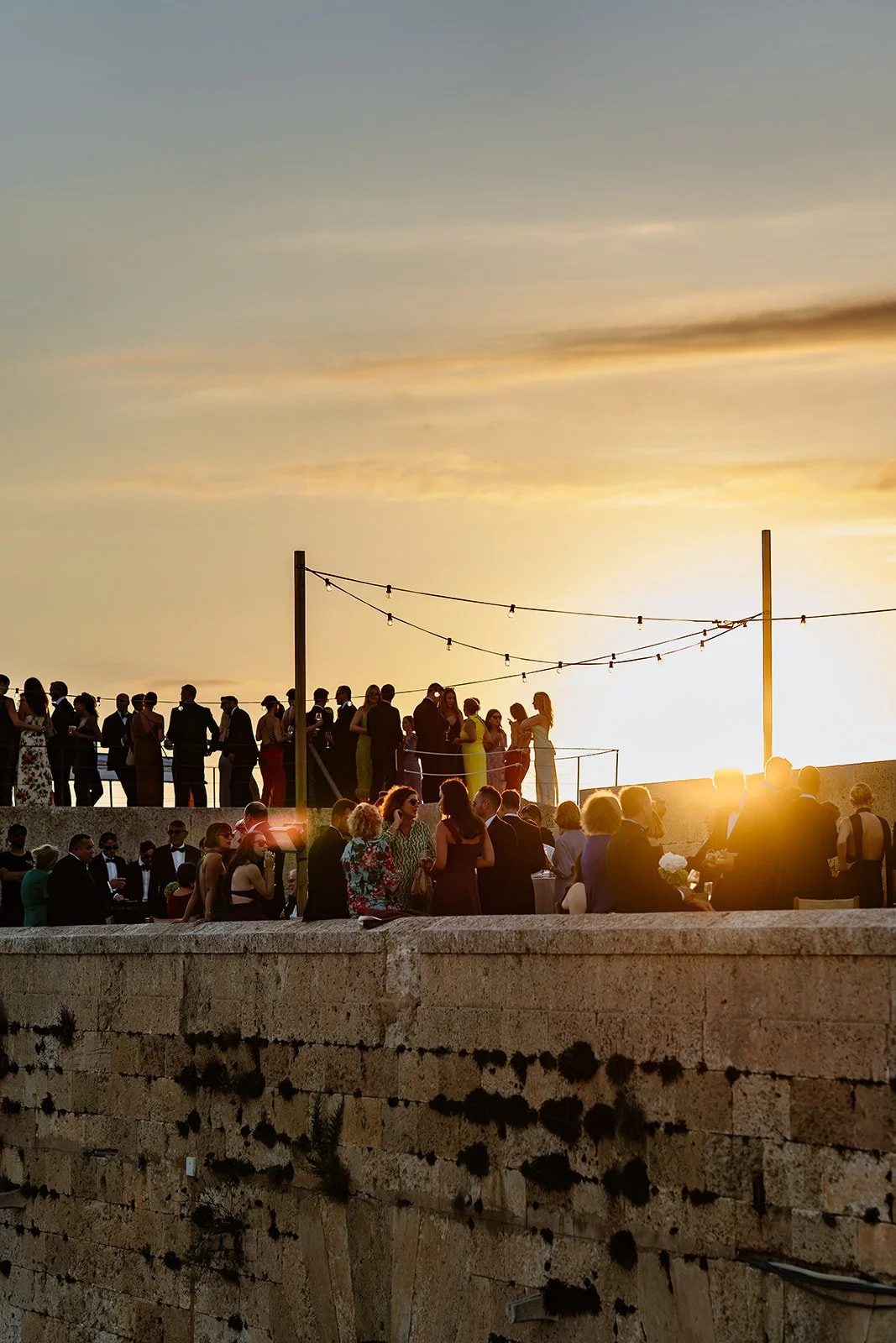 Guests gathering at sunset on a historic fort overlooking the sea during a destination wedding in Menorca