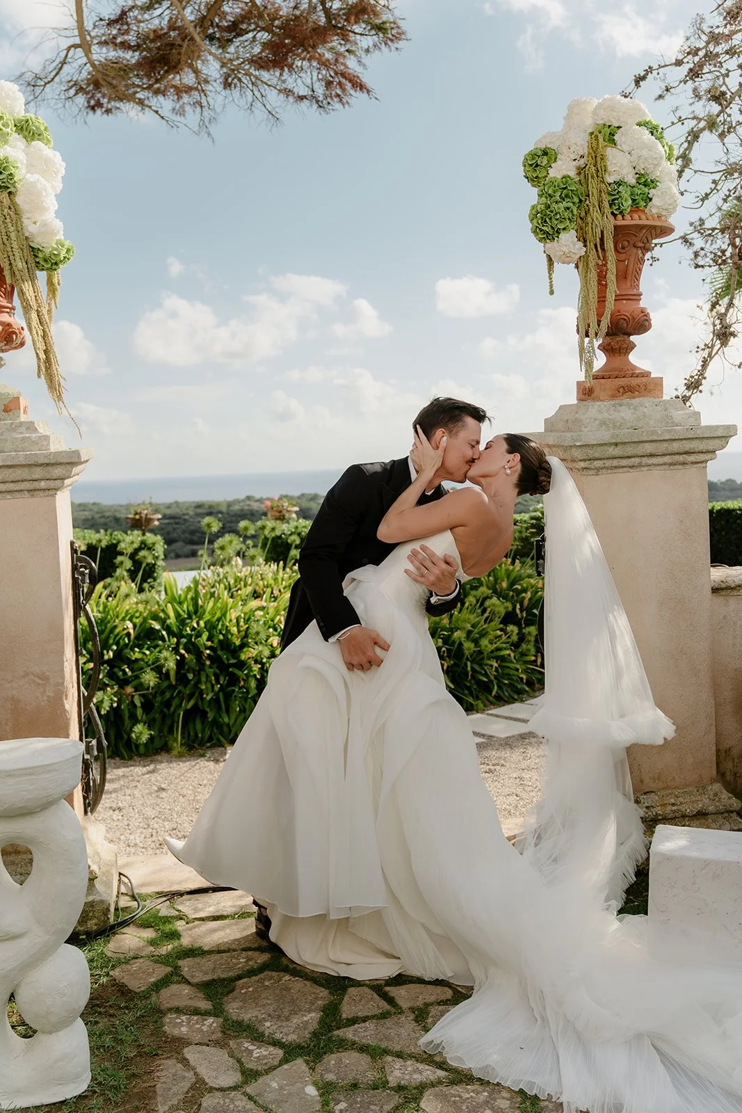 Couple kissing during wedding ceremony on terrace overlooking Menorca landscape