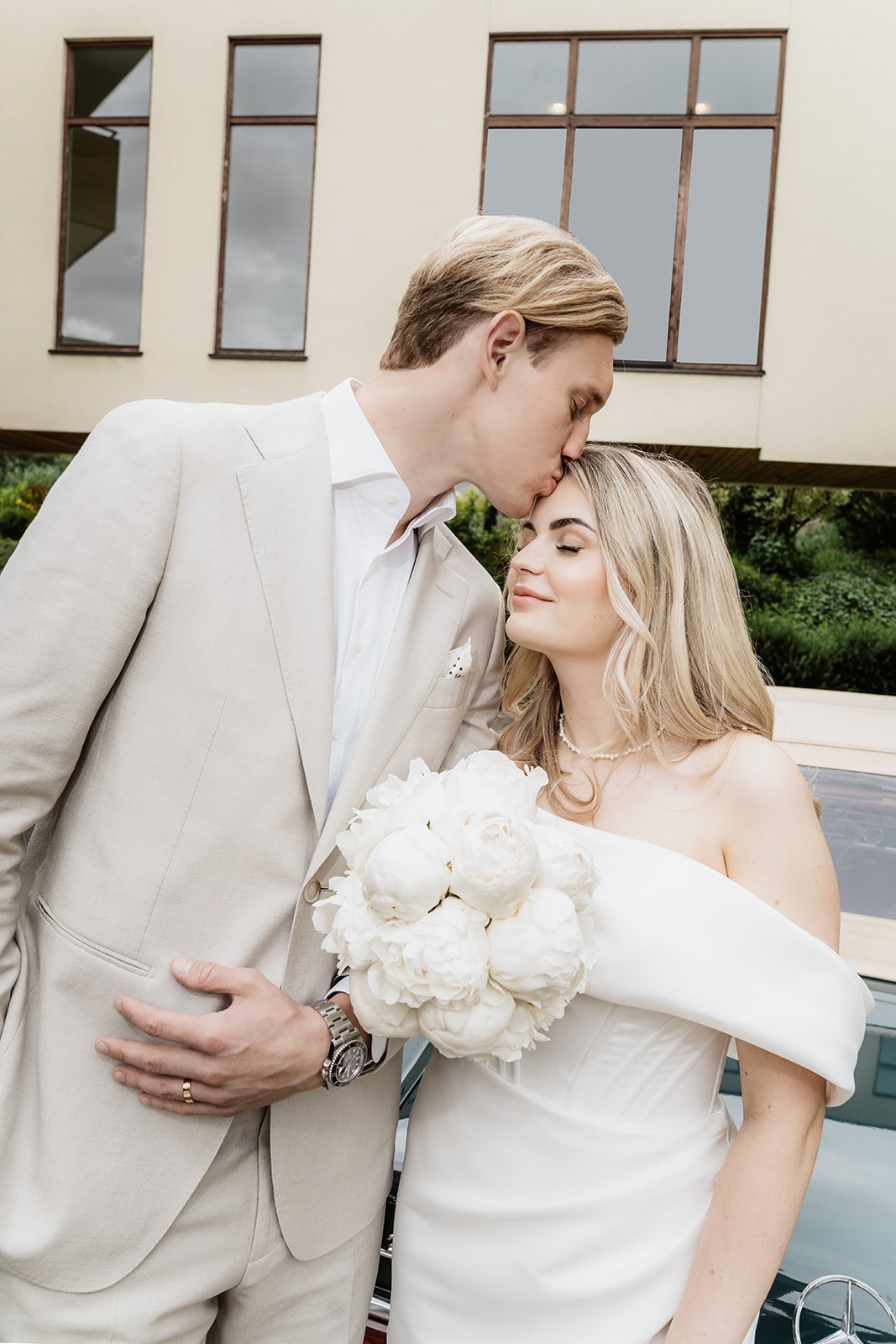 Bräutigam küsst die Braut liebevoll auf die Stirn vor dem Hotel Lengbachhof während ihrer Hochzeit in Niederösterreich.
