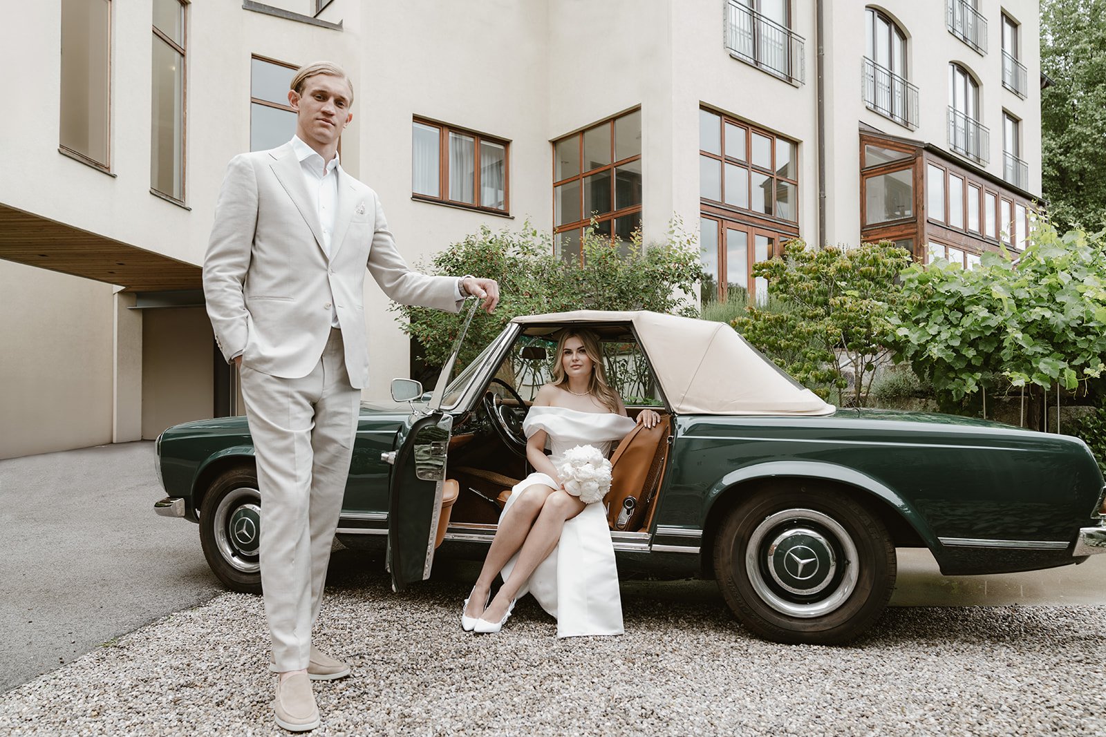Editoriales Brautpaarporträt mit einem Vintage Mercedes vor dem Hotel Lengbachhof.