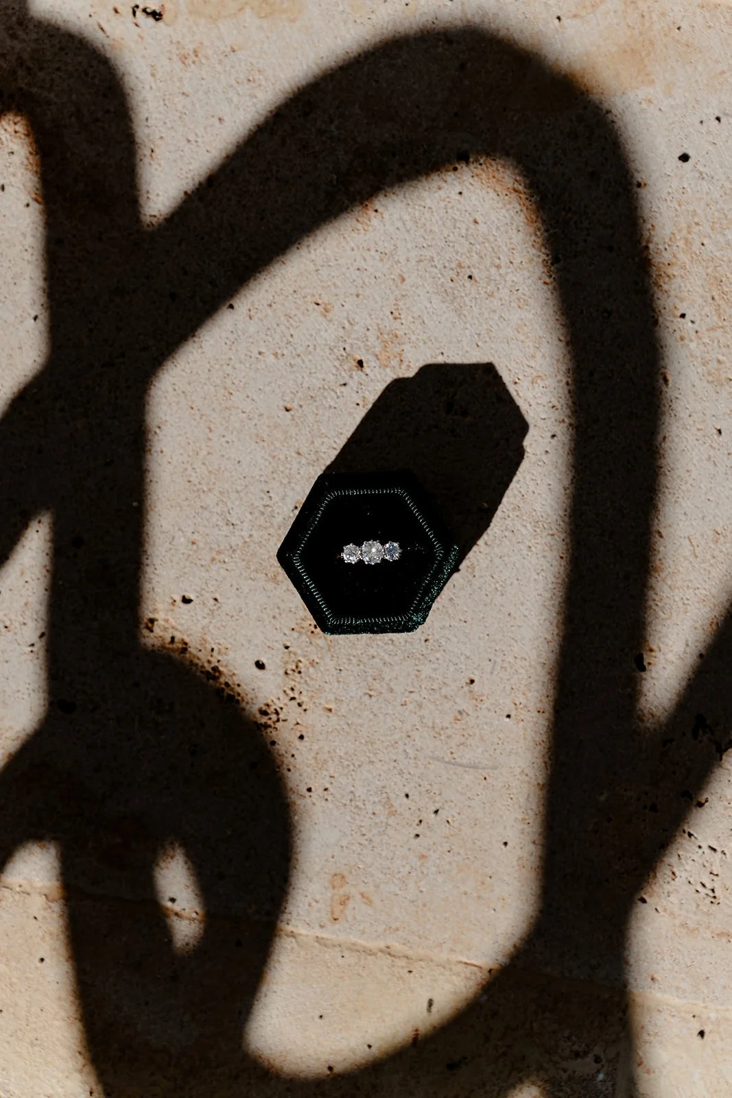 Wedding rings in box with dramatic shadows on stone surface in Menorca