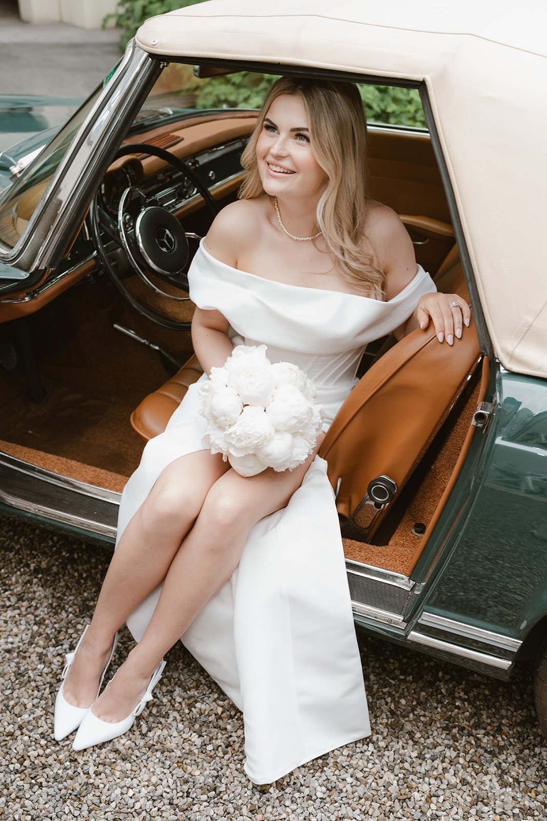 Braut sitzt lächelnd in einem klassischen Mercedes-Oldtimer während ihrer Hochzeit im Hotel Lengbachhof.