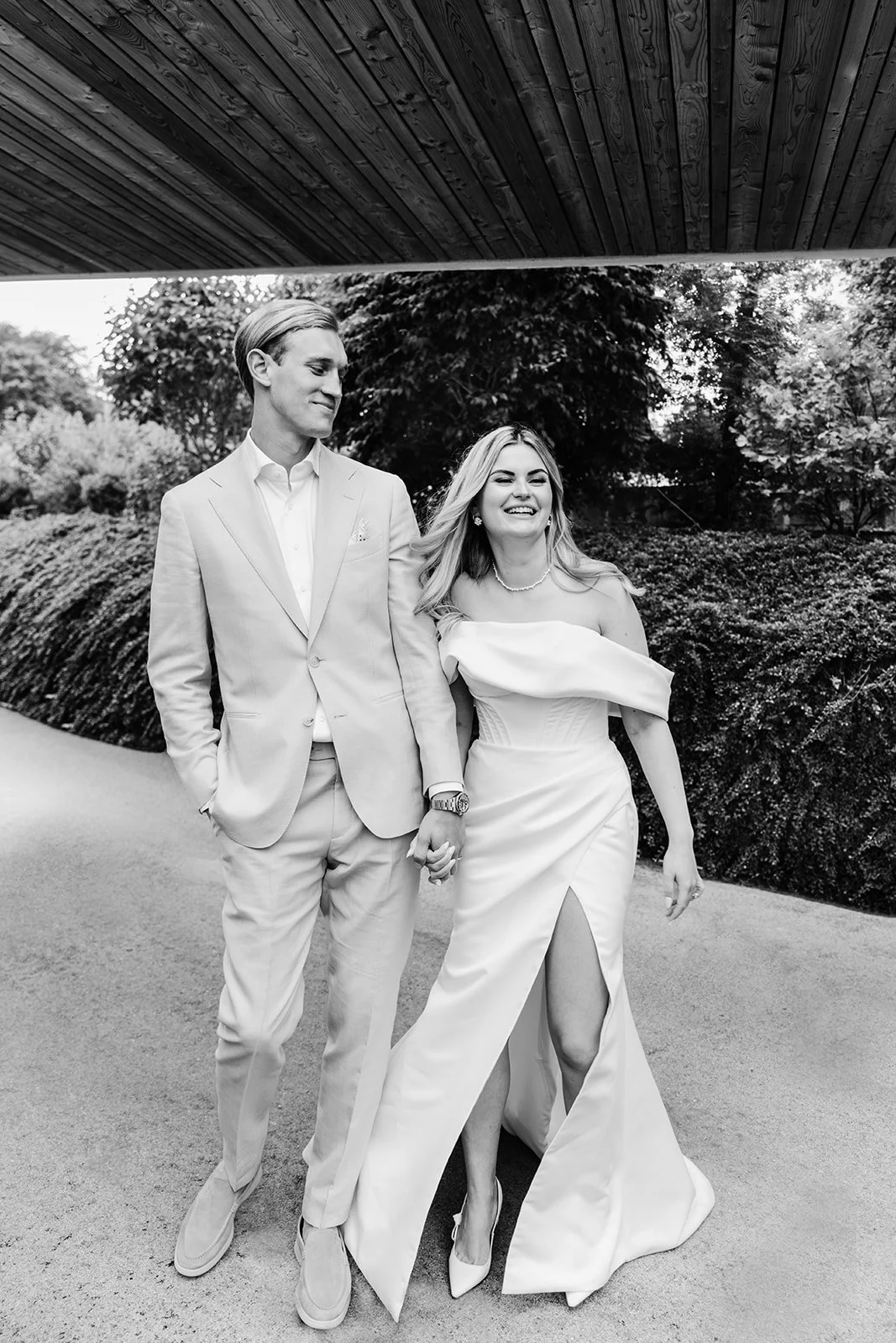 Braut und Bräutigam spazieren lachend Hand in Hand während ihrer Hochzeit im Hotel Lengbachhof in Niederösterreich.