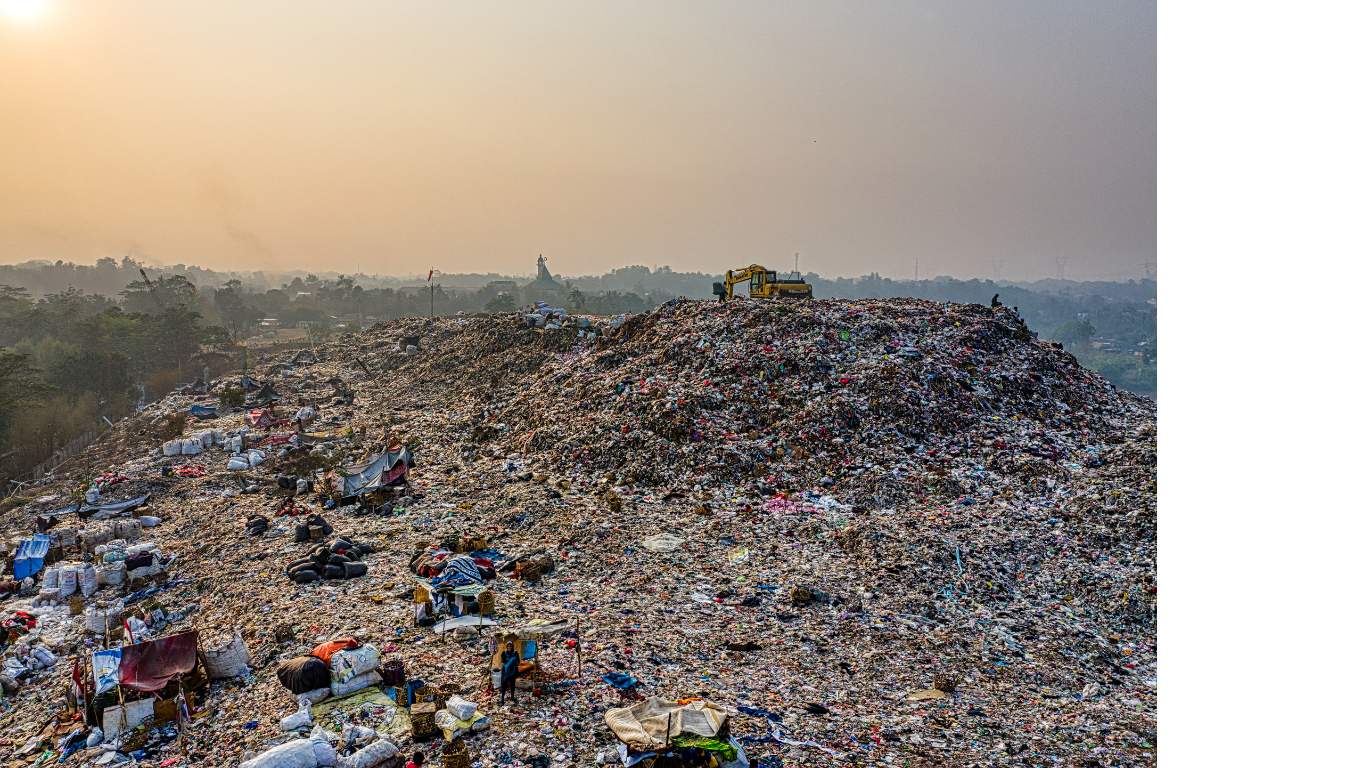 A large landfill site filled with trash, waste debris, and scattered makeshift tents, with an excavator on top, under a hazy sky.