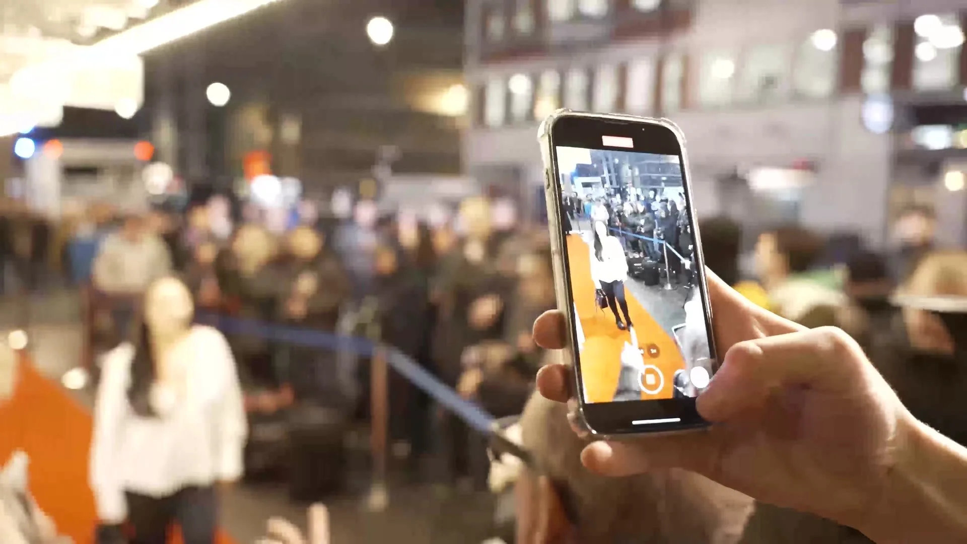 A fan filming arrivals on a phone