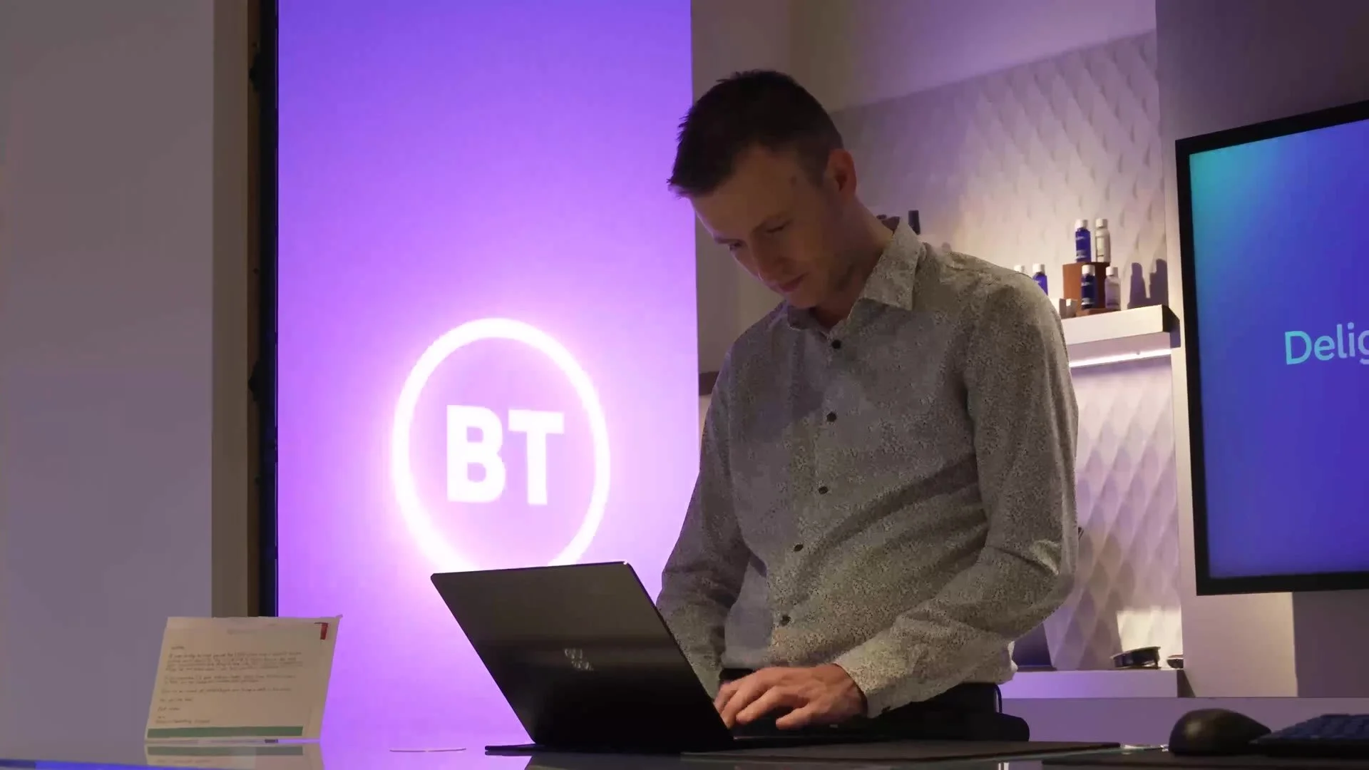 Presenter at a laptop in front of a BT screen