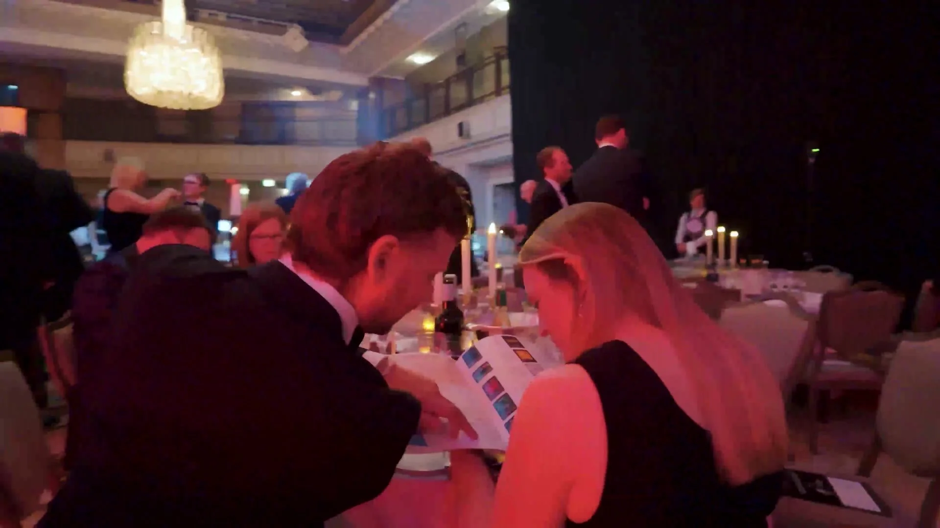 Guests reading the programme at dinner during the HealthInvestor Awards