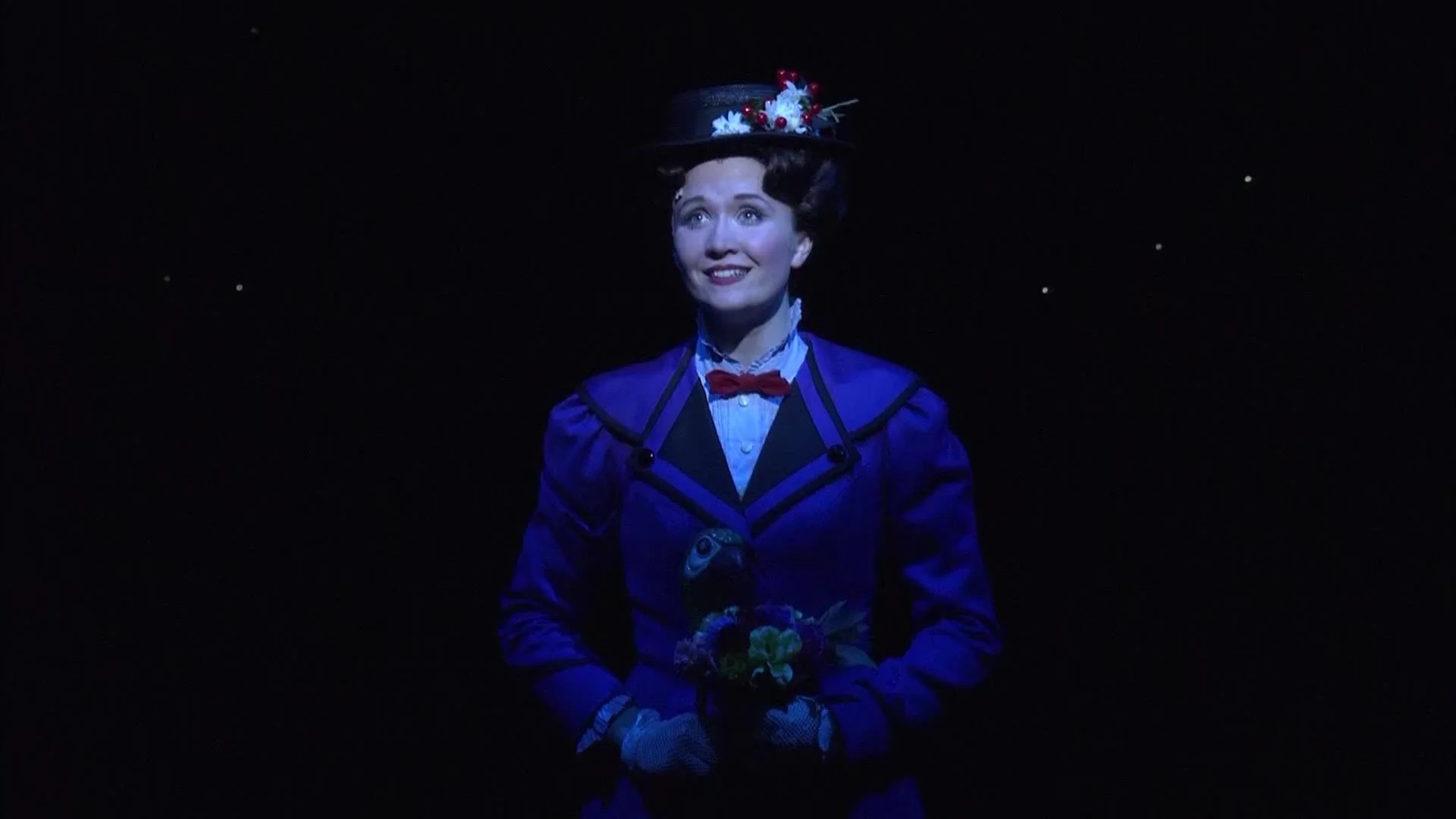 Mary Poppins on stage under a blue spotlight