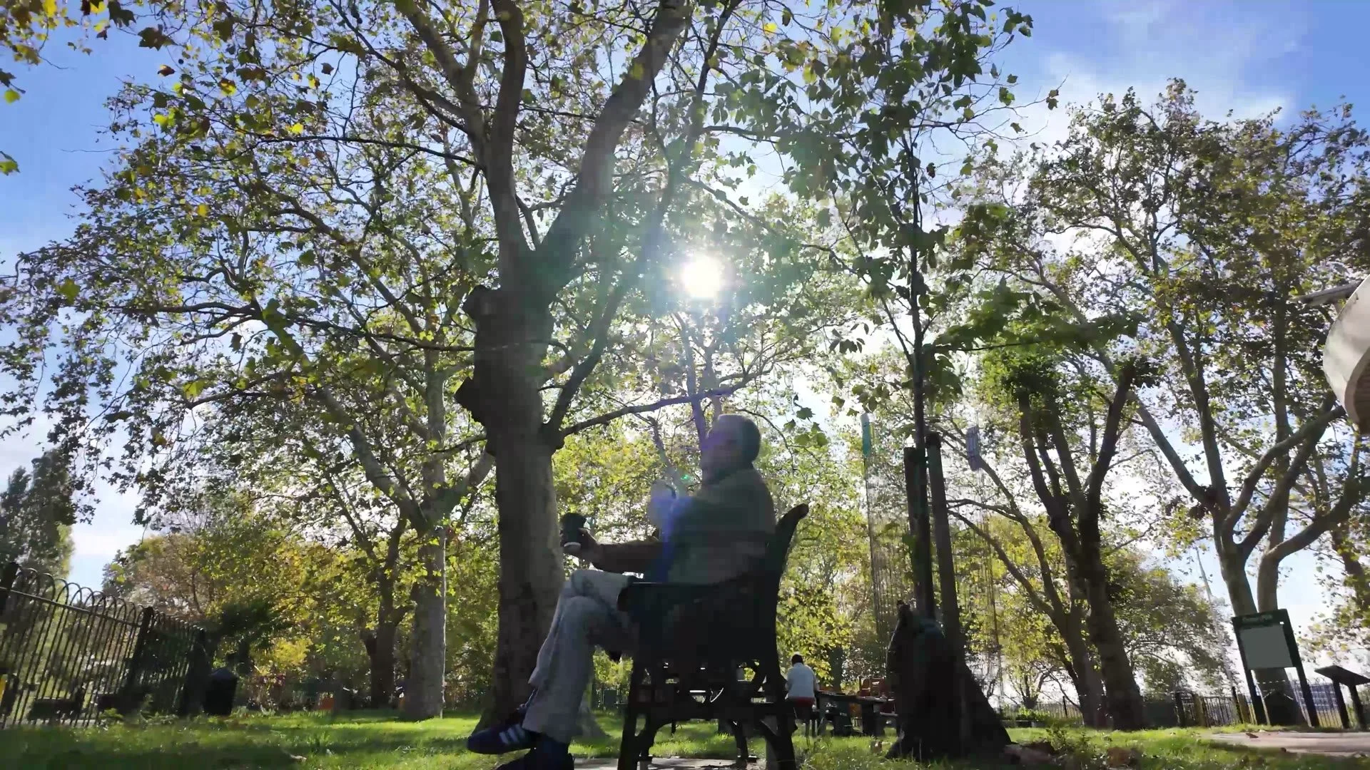 Michael sitting on a park bench under the trees