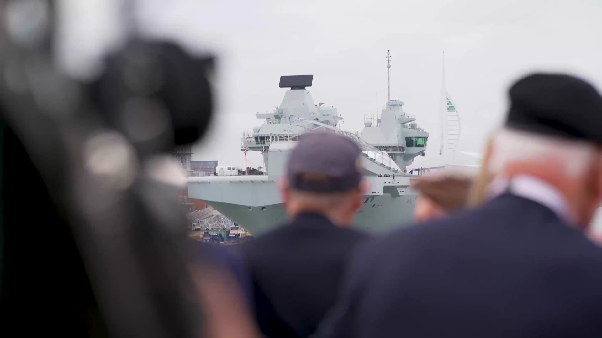 Veterans waving as they pass a warship