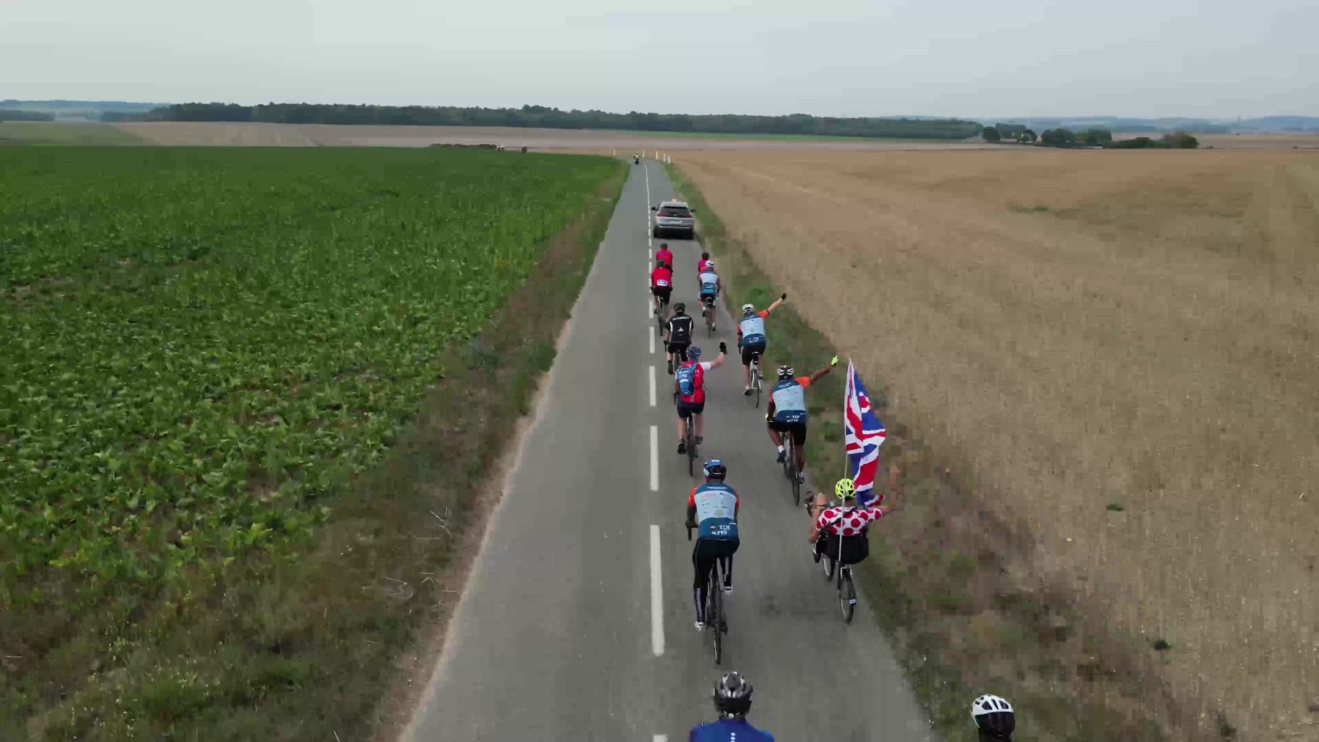 Riders carrying a Union flag along a country road