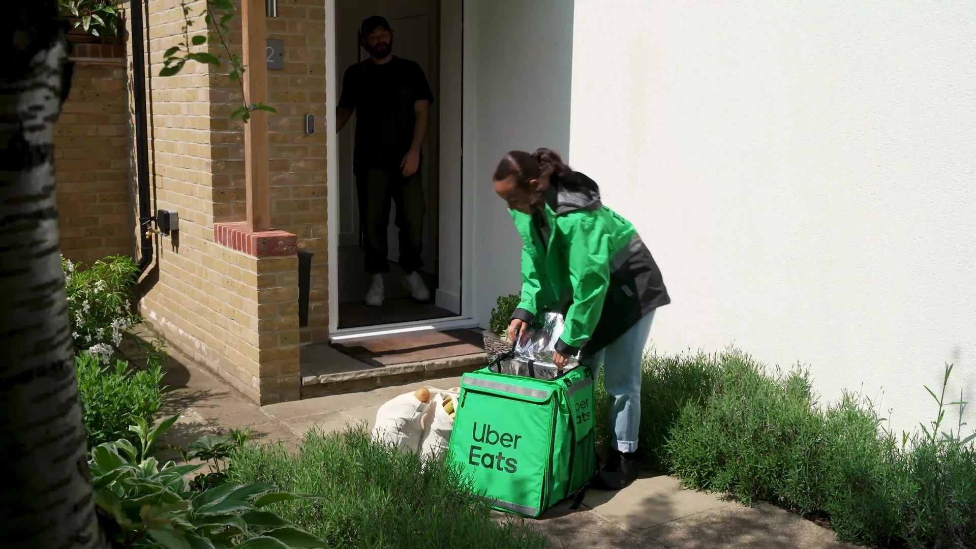 Uber Eats courier delivering an order to a front door, with a dog in the doorway
