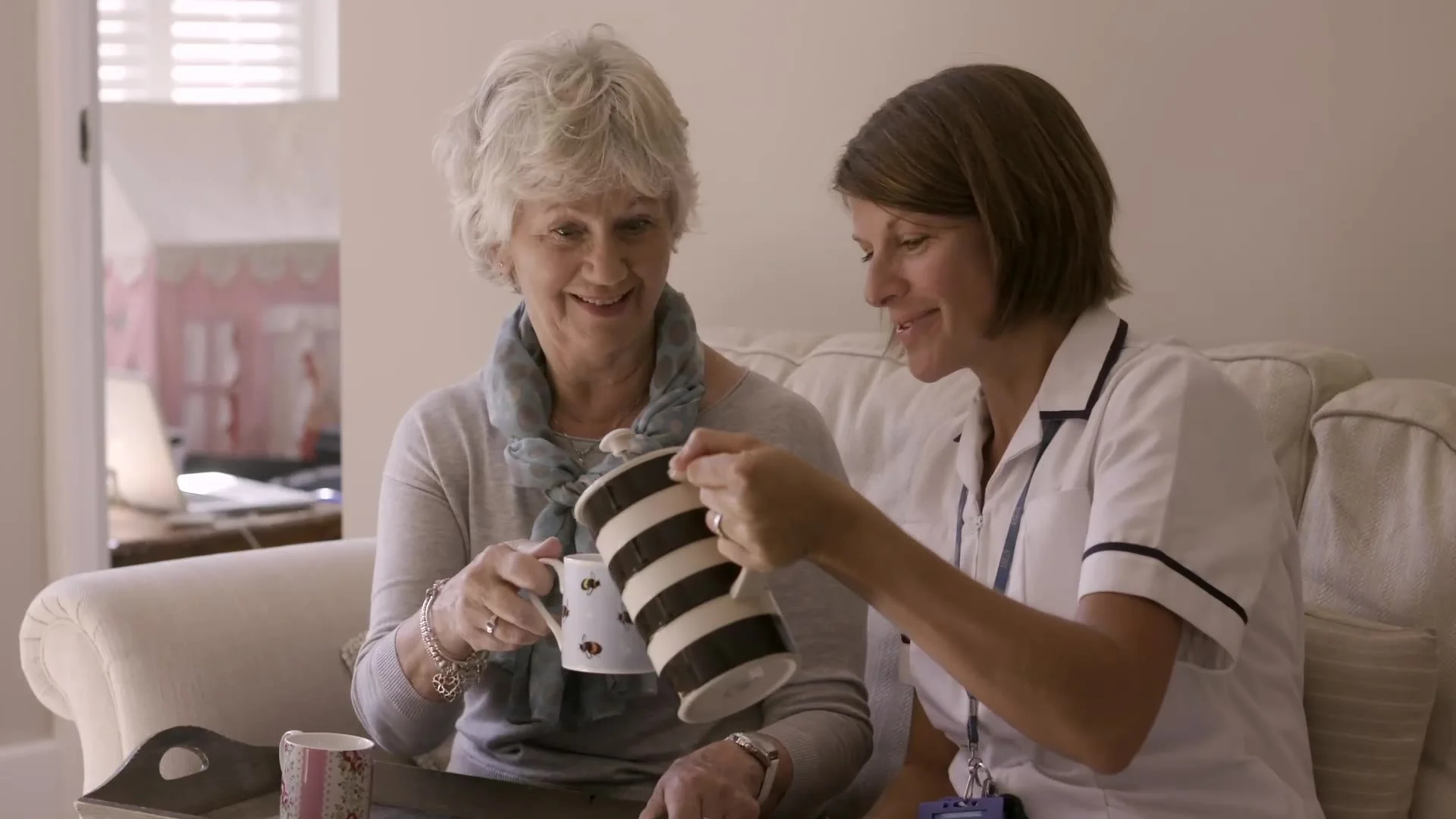 A nurse sharing tea with a patient at home