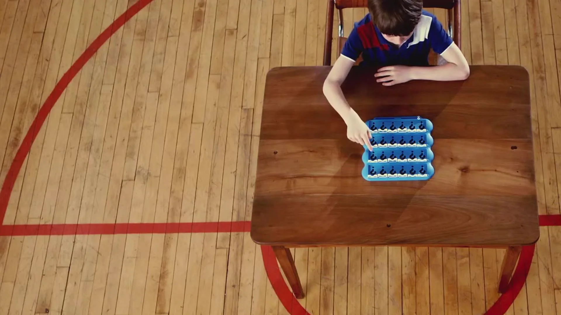 Overhead shot of a boy at a desk in the middle of a sports hall, from the Octopus Energy advert
