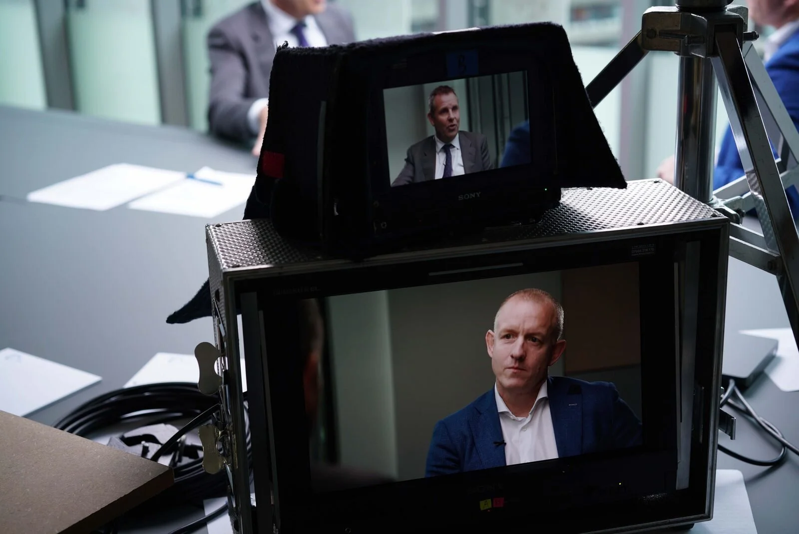 A camera monitor framing a boardroom interview