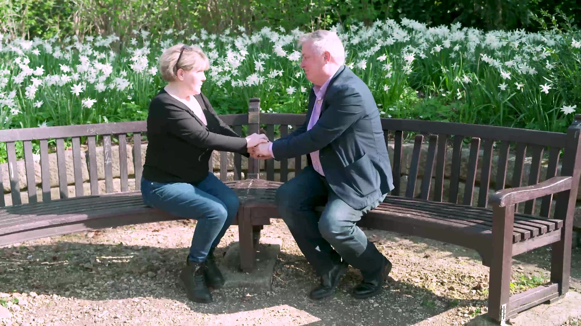 Lee and Jennifer holding hands on a garden bench
