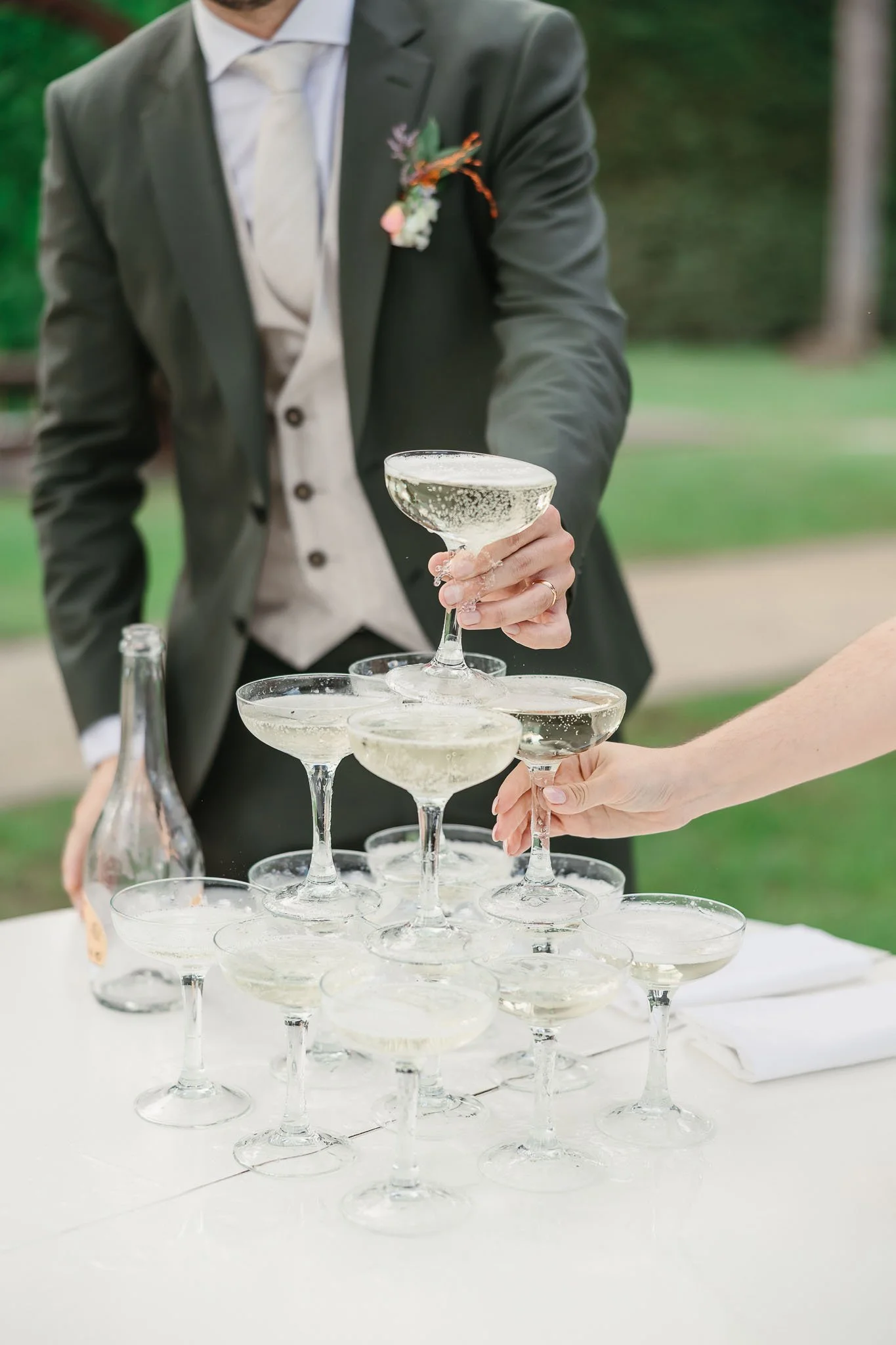 People toasting with champagne glasses stacked in a pyramid during a celebration.