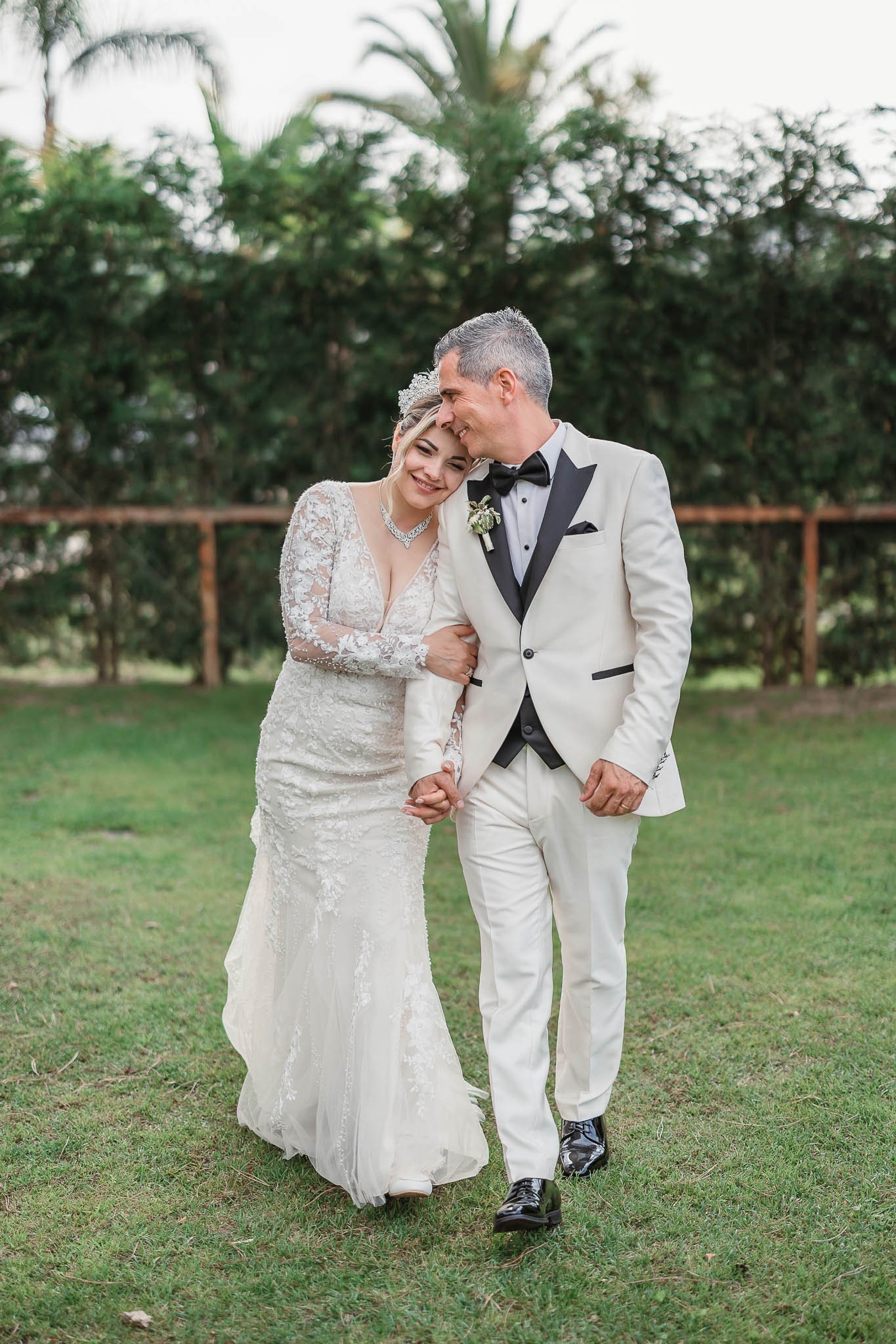Portuguese Wedding Photographer:   A bride and groom dressed in wedding attire walking arm in arm outdoors, smiling and laughing together.