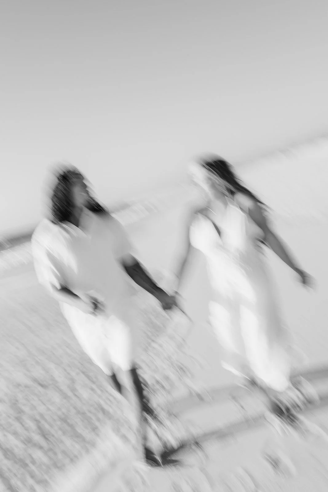 A blurred black-and-white photo of a couple holding hands on a beach, captured by a Portugal wedding photographer.
