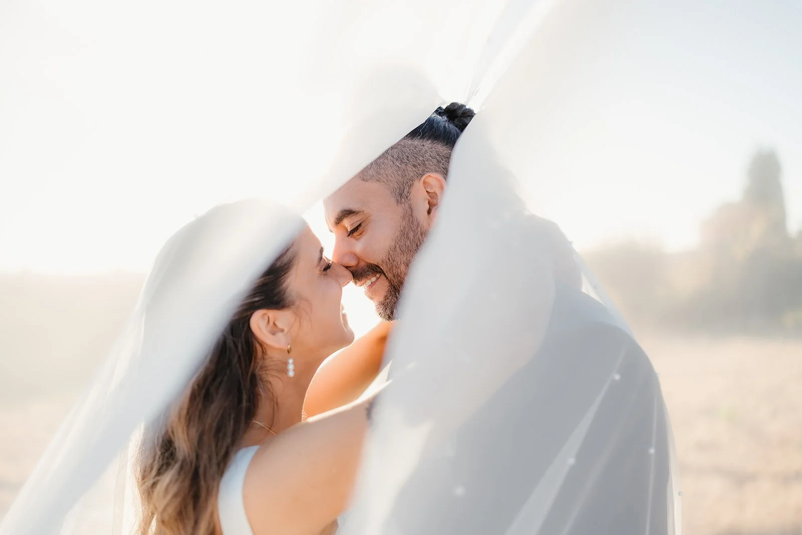 Bride and groom smiling, touching noses under a flowing veil—Portugal Wedding Photography captures their magical outdoor moment.