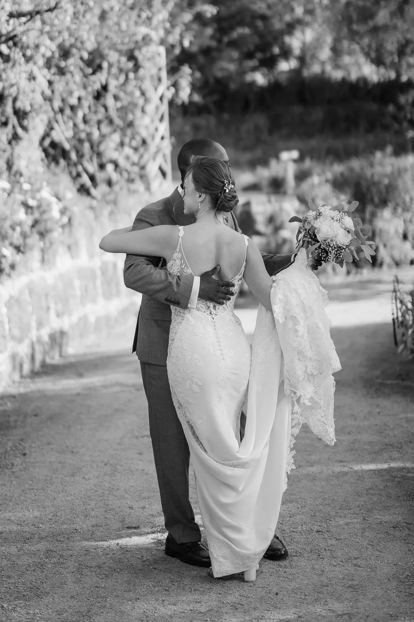 Destination Wedding Photographer Portugal - A bride and groom embrace outdoors on their wedding day, with the bride holding a bouquet of flowers, both dressed in wedding attire.