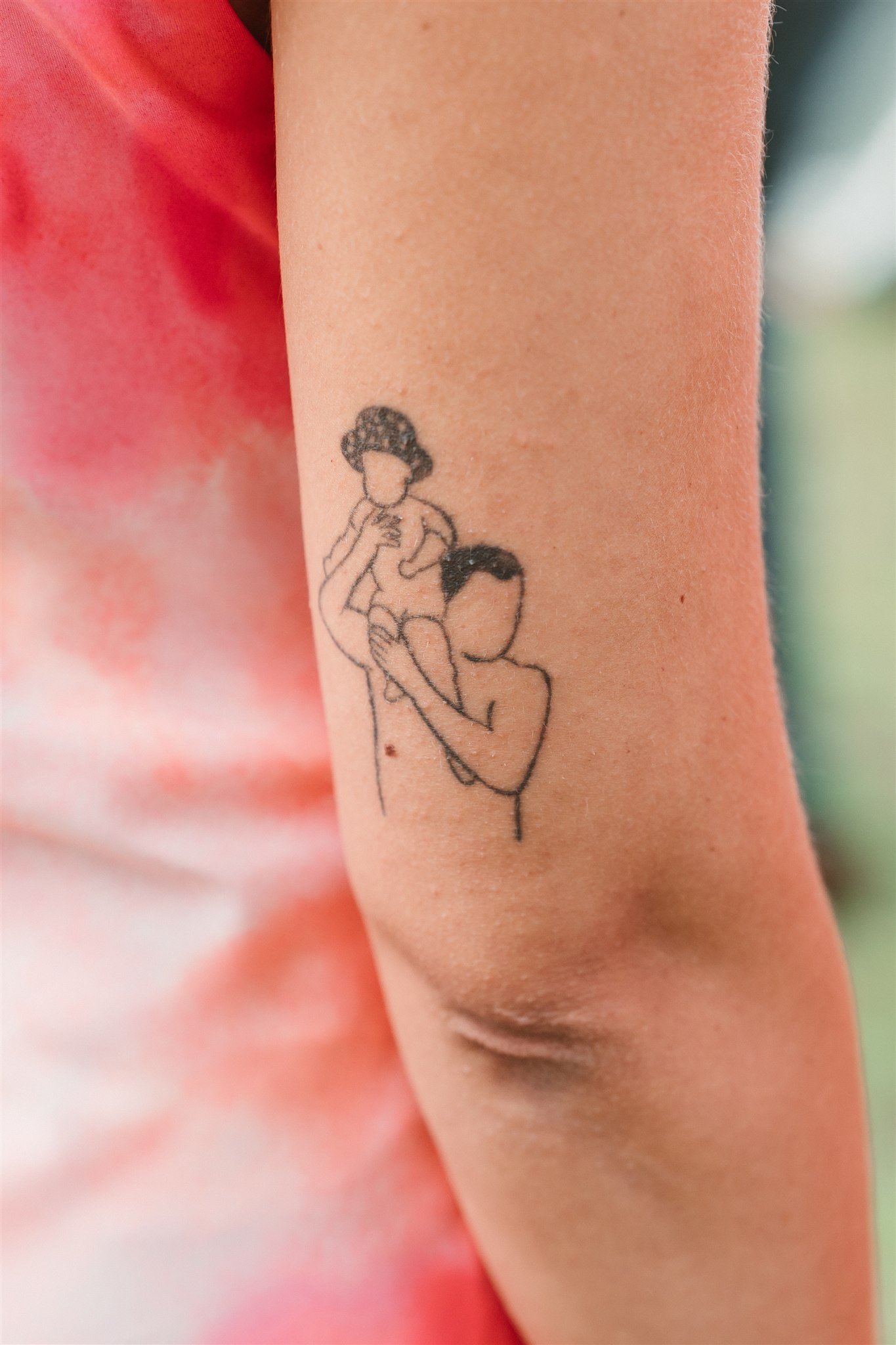 Minimalist tattoo of an adult lifting a child, inked on an arm—perfect inspiration for a Portugal Wedding Photographer.