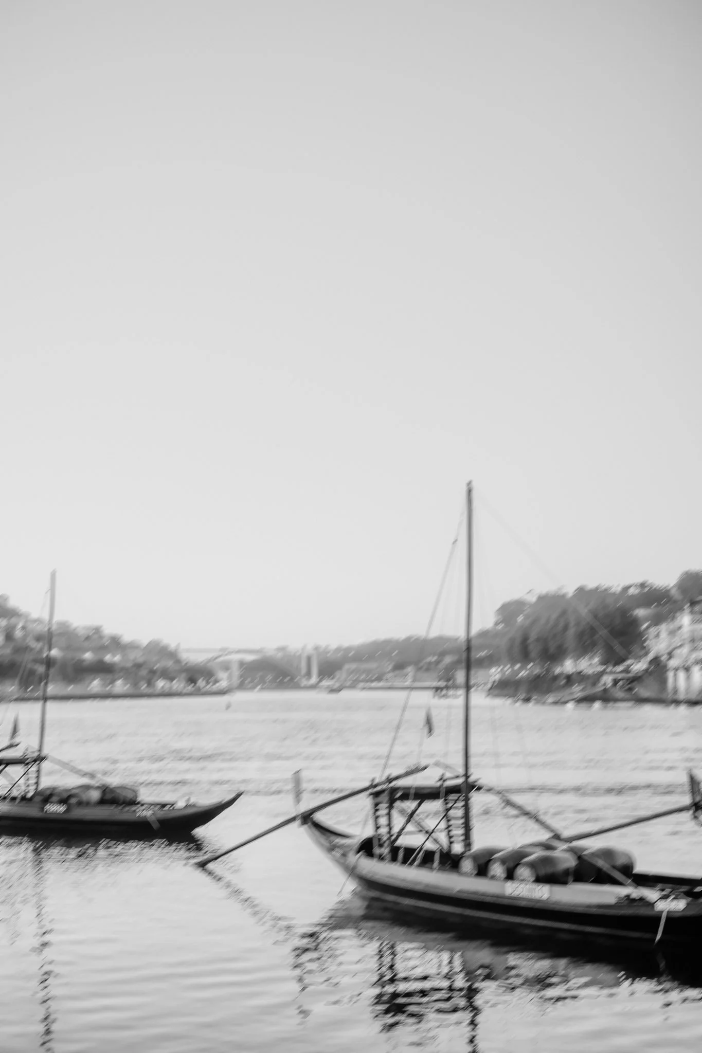 Two traditional wooden boats float on a calm river, capturing the serene beauty a Portugal wedding photographer might seek. Porto