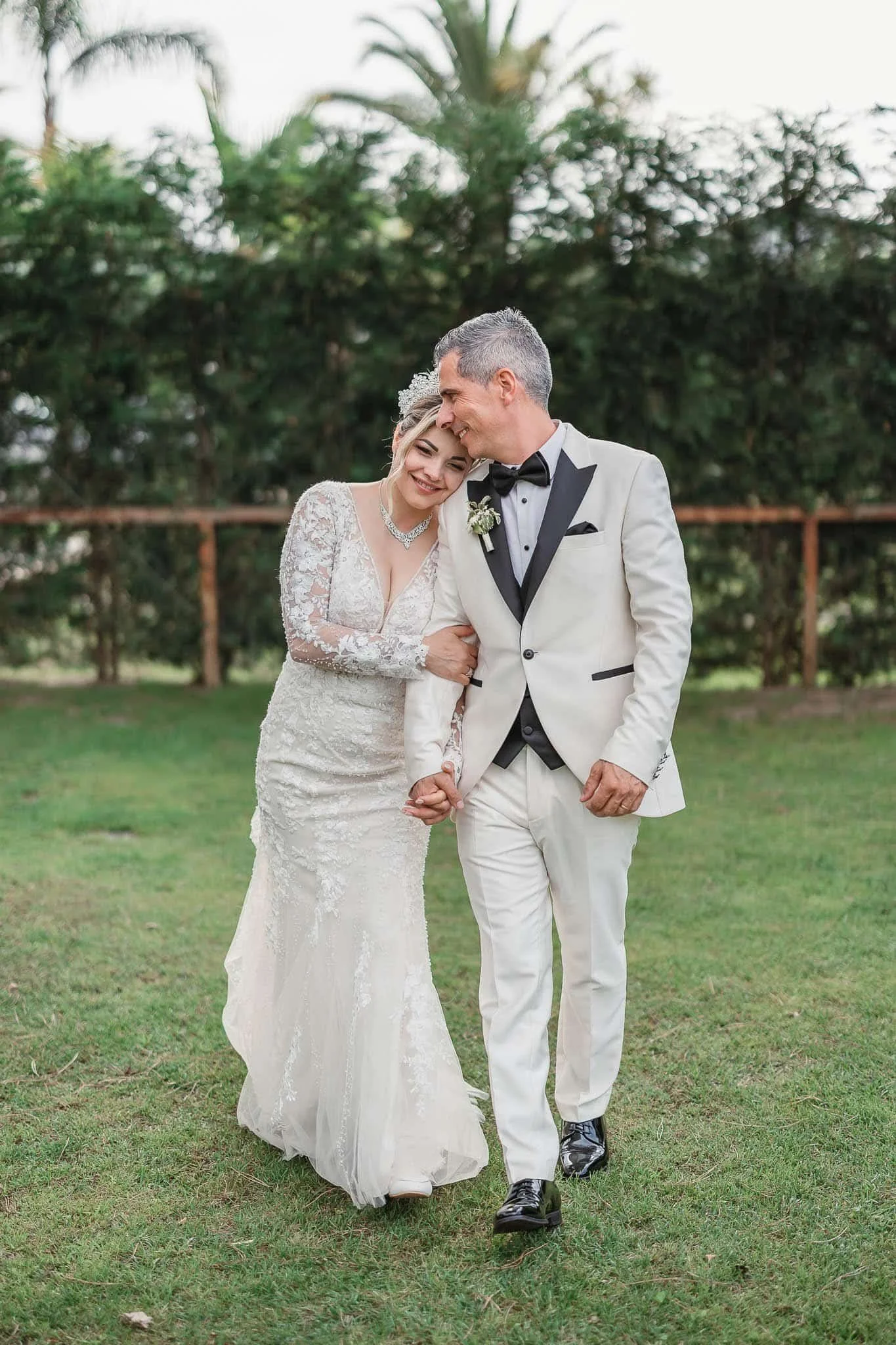 Portuguese Wedding Photographer:   A bride and groom dressed in wedding attire walking arm in arm outdoors, smiling and laughing together.