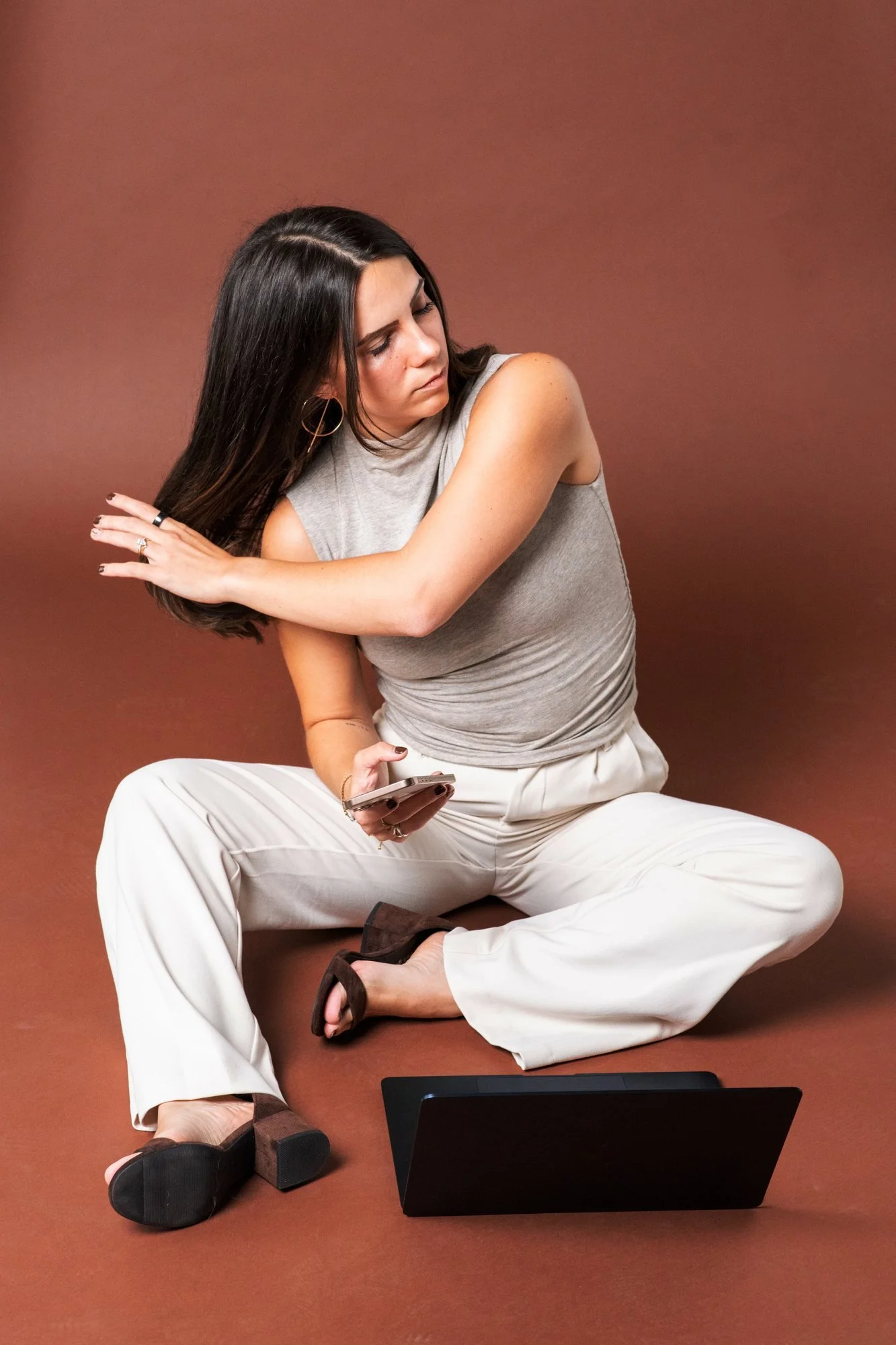 Sky sitting on the floor with her phone and laptop, pushing her hair back
