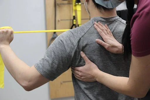Physiotherapist assisting a person with shoulder therapy using a resistance band