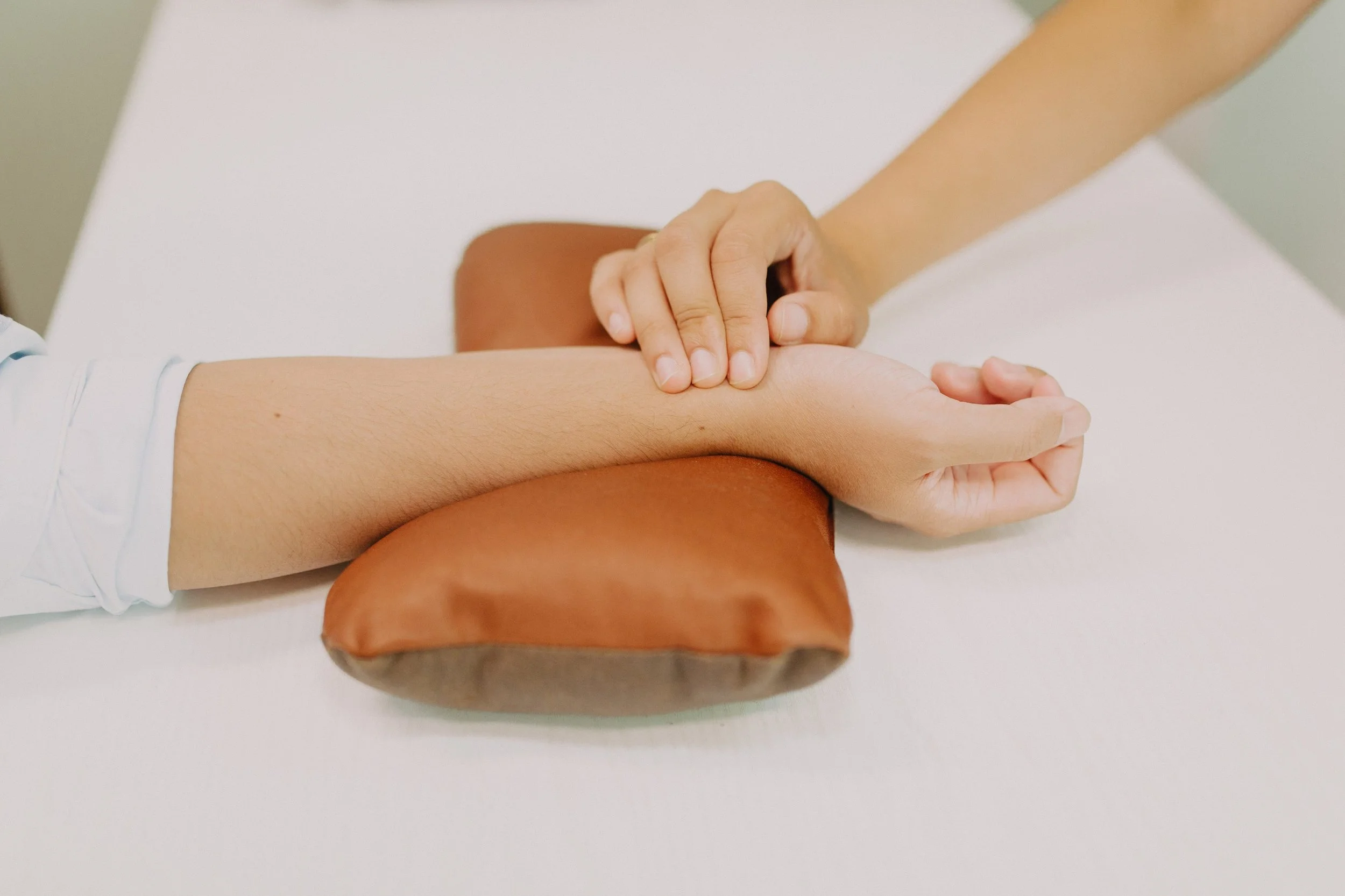 A person receiving a massage on their arm at a spa or therapy session, with their arm relaxed on a white surface.