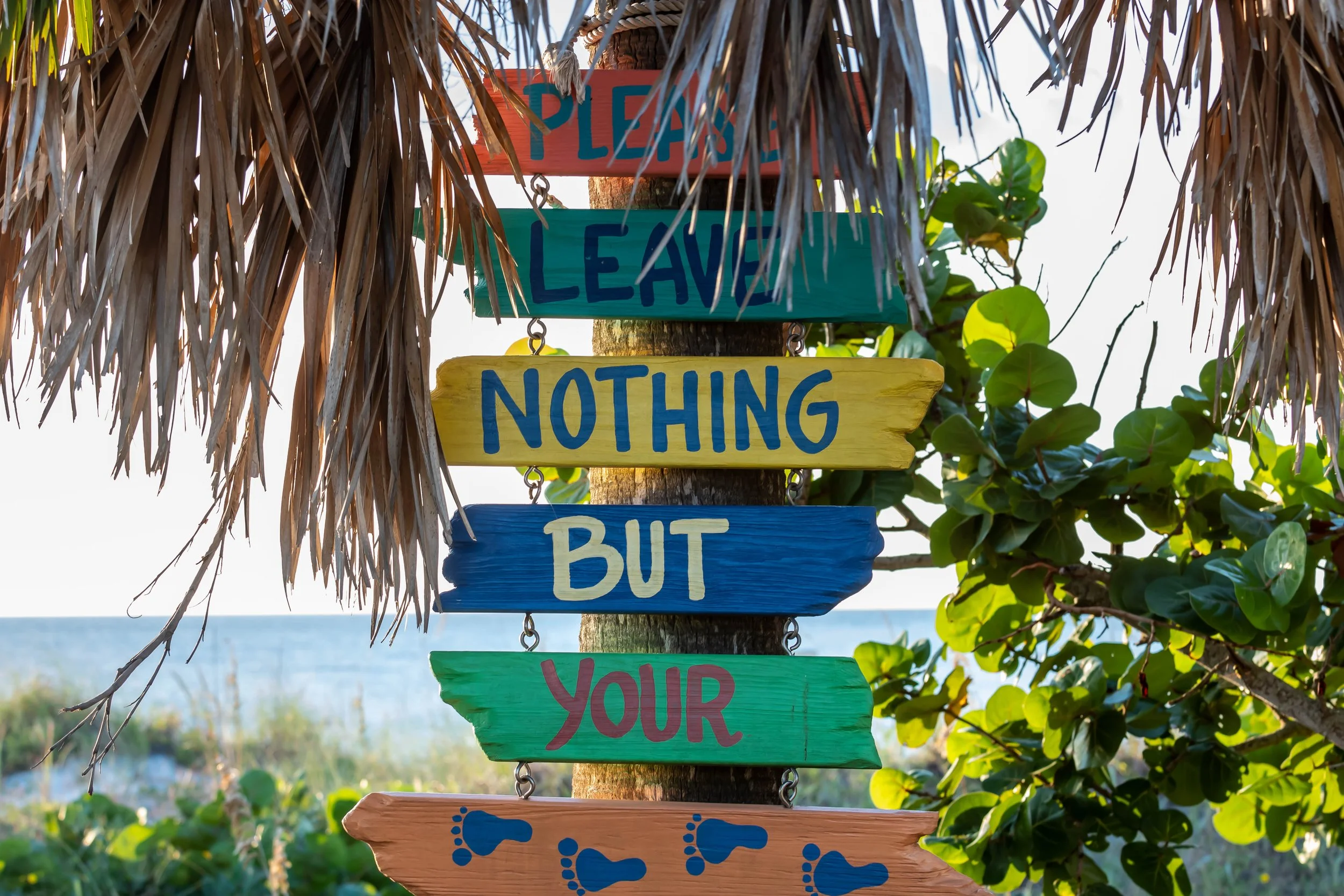 Colorful beach sign reading “Please leave nothing but your footprints” near Indian Rocks Beach