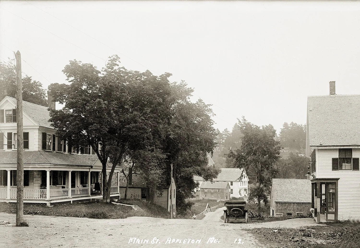 McLain’s Mills (Appleton Village), Me 
This photo shows McClain’s Mills, now Appleton Village, looking east from the head of Sennebec Road and Elm Street and Town Hall Road.  At the left, in the trees, is visible the porch of the Sumner/Gushee house,