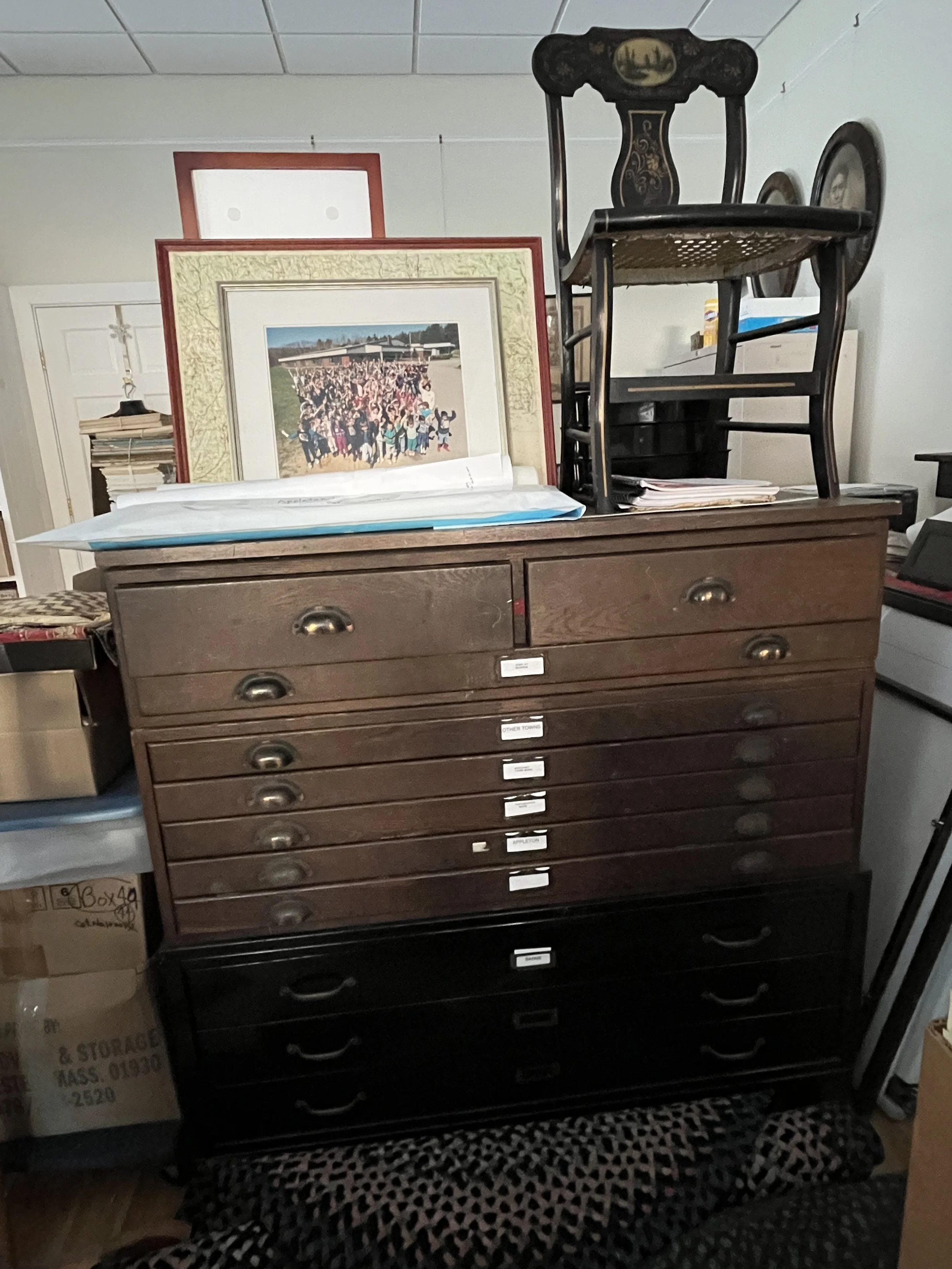 Flat files containing maps and documents. Atop the flat file is a Hitchcock-style chair, painted by well known Appleton painter, Uriah Dyer.