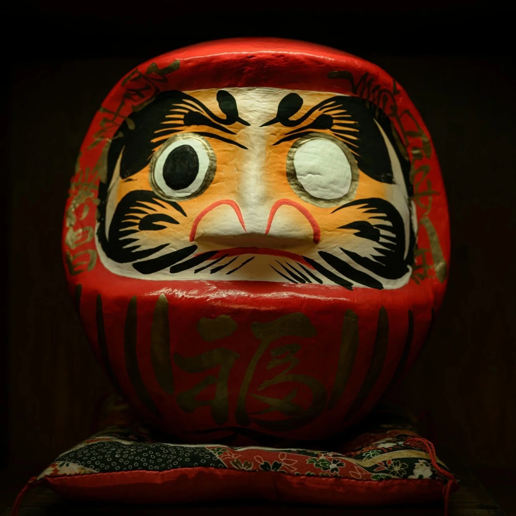A traditional Japanese Daruma doll resting on fabric, symbolizing intention, perseverance, and cultural heritage.