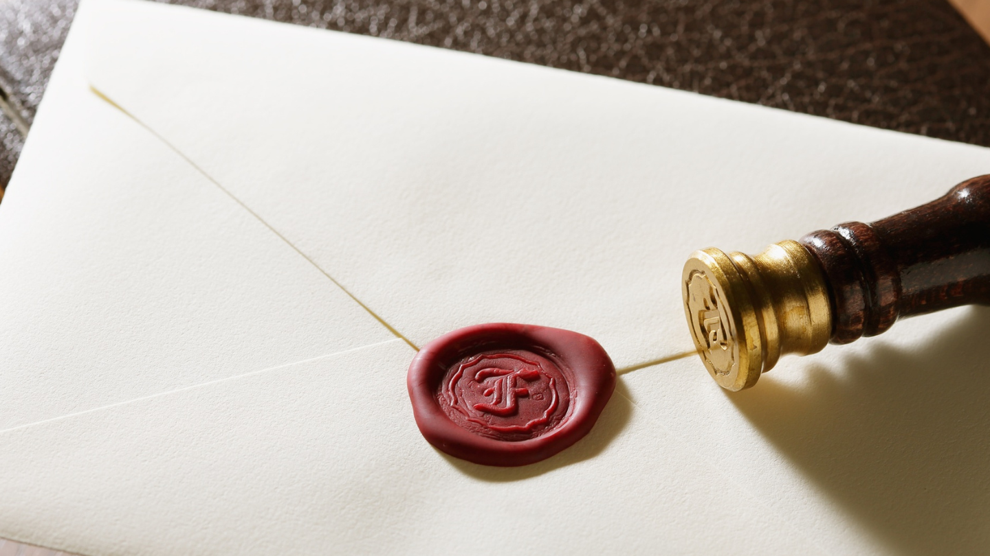 Envelope with wax seal and wax seal stamp.