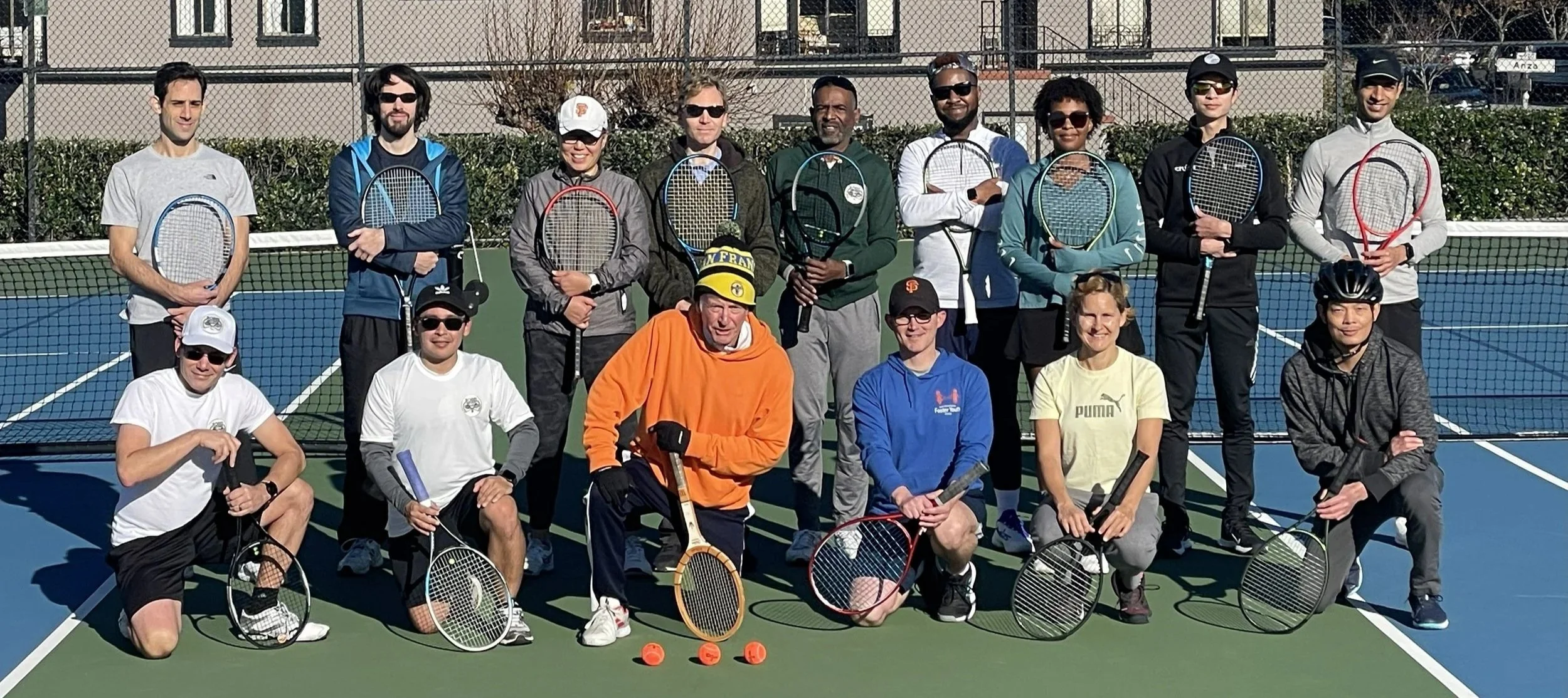 Group of Rossi Racquet Club tennis players posing with rackets on outdoor court
