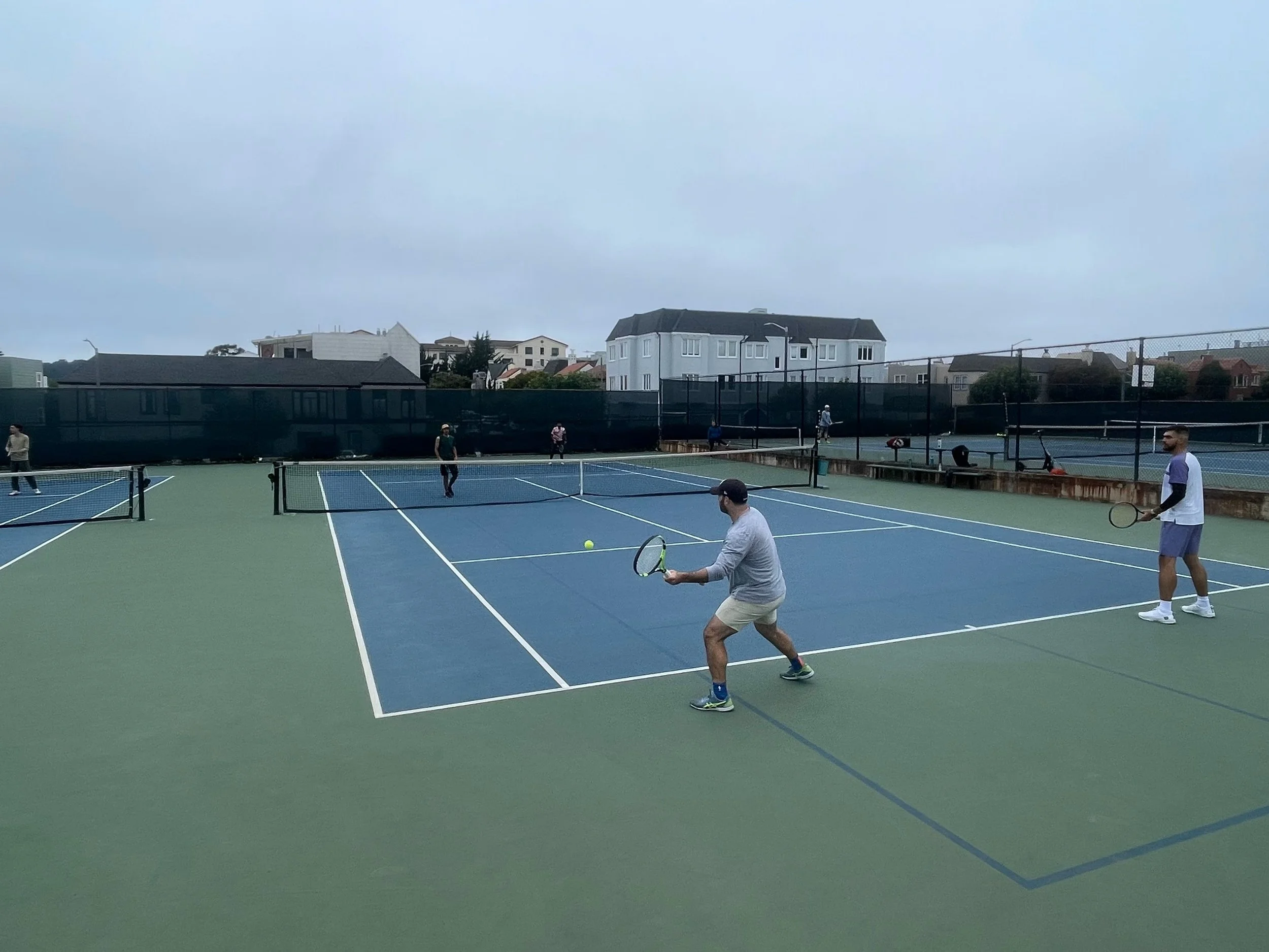 Action shot of doubles tennis match with players at Rossi Park