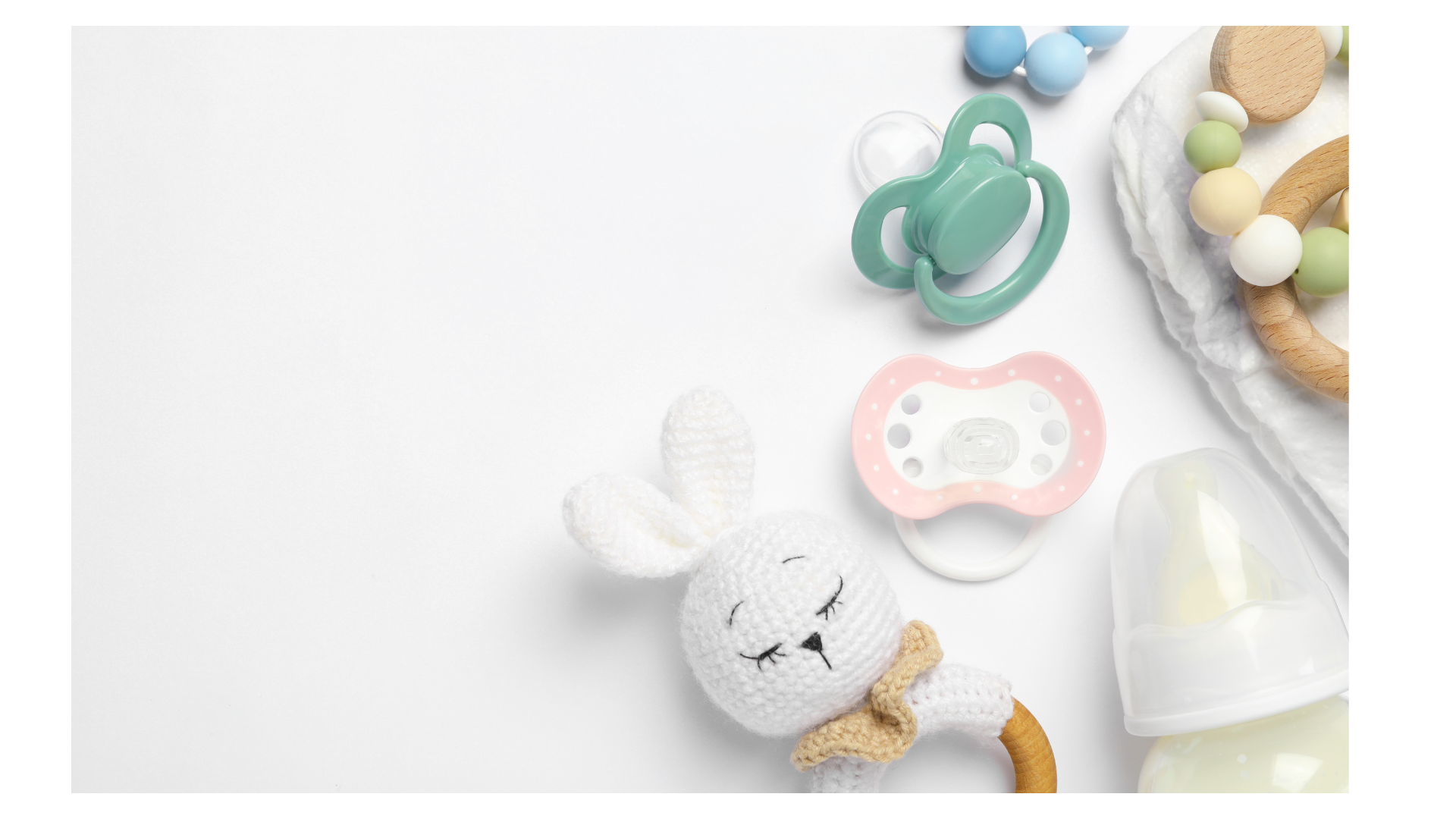 A collection of baby items including a plush bunny toy, a pink and white pacifier, a green pacifier, a teething ring with beads, a baby bottle, and a cloth on a white background.