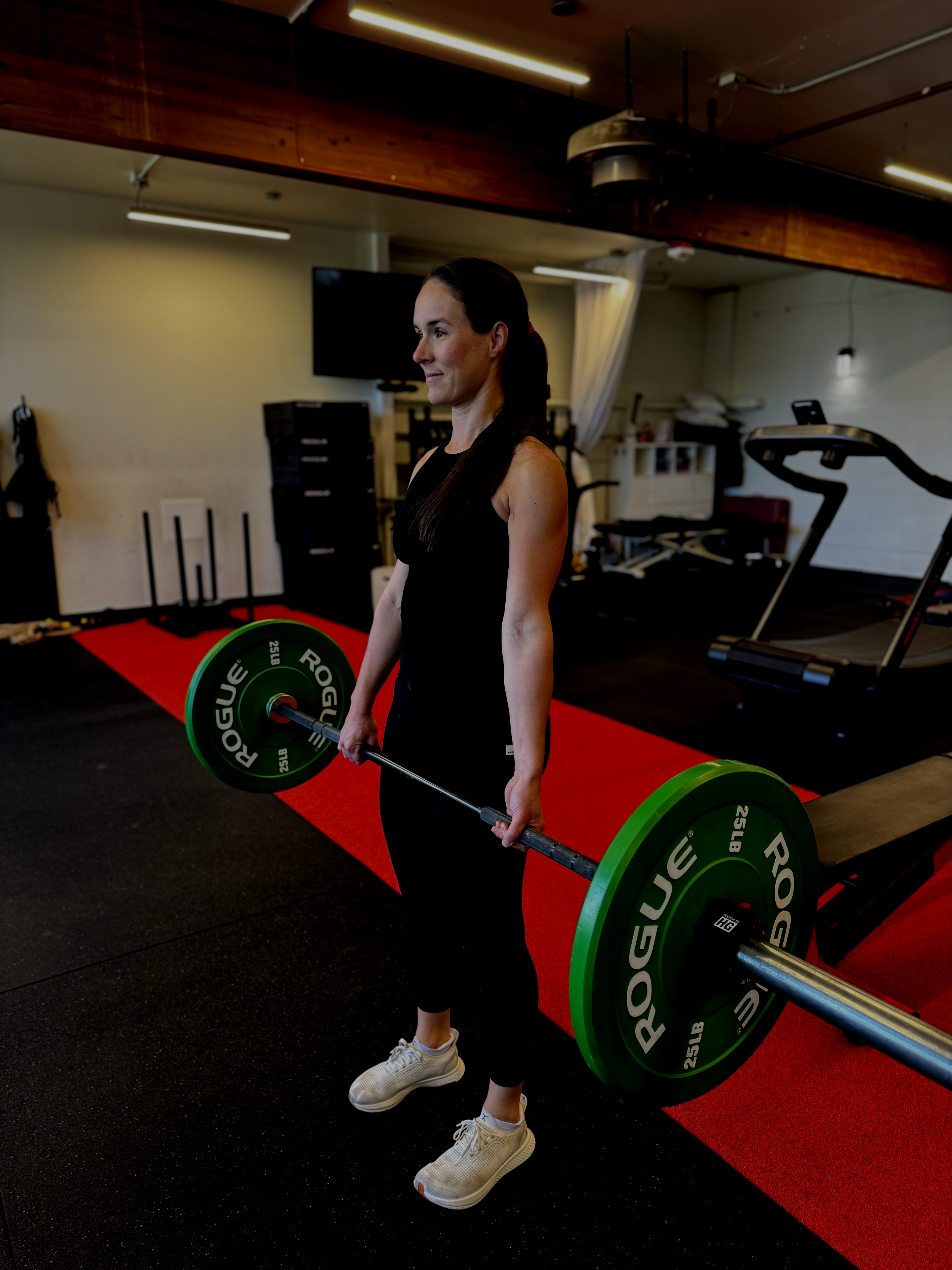 A woman lifting a barbell in a gym.
