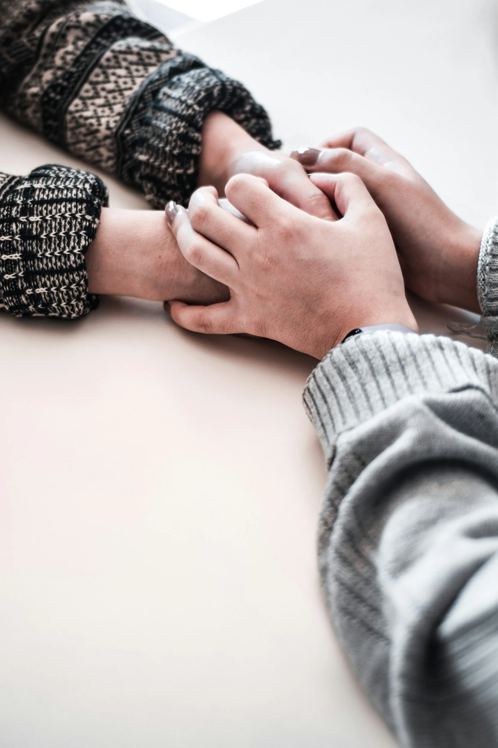 Two people holding hands, one gently grasping the other's wrist.