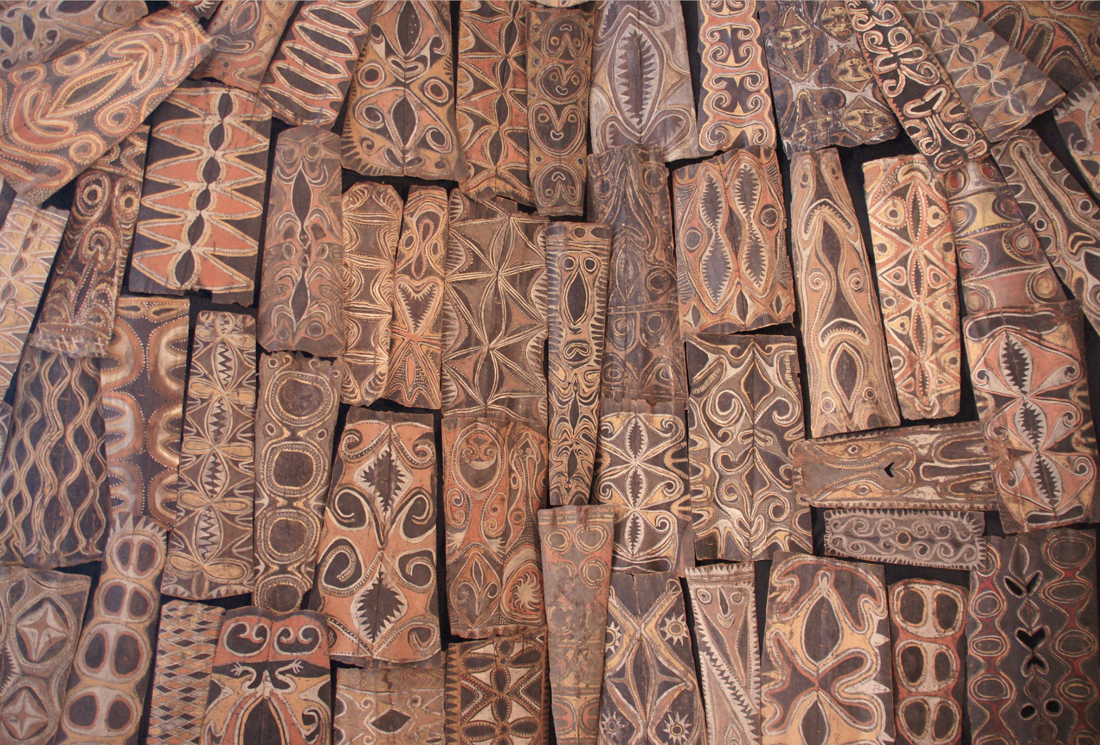 Close-up of rectangular wooden panels with Polynesian tribal patterns, arranged in a collage.